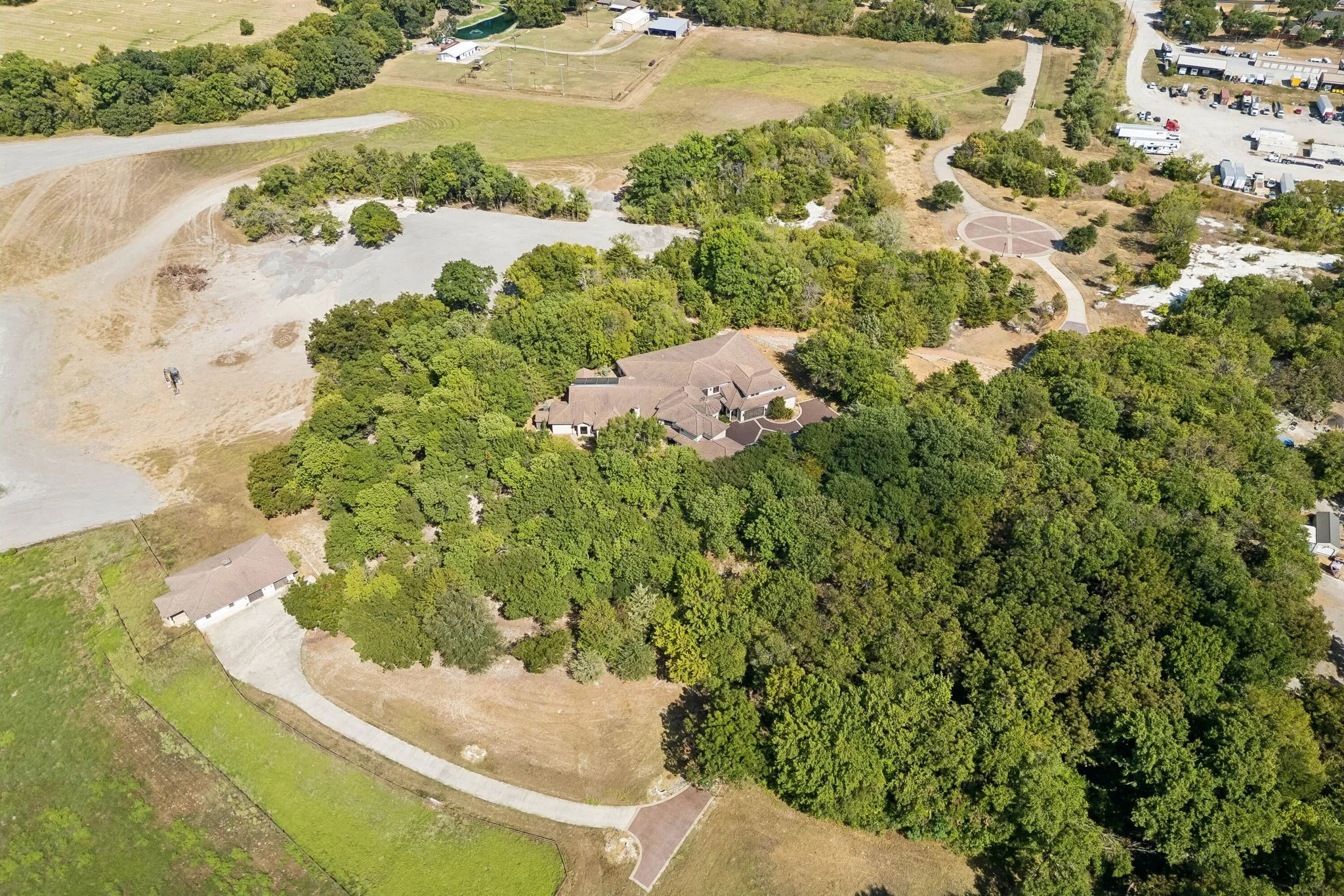 Home surrounded by trees with secondary driveway down to barn and pasture