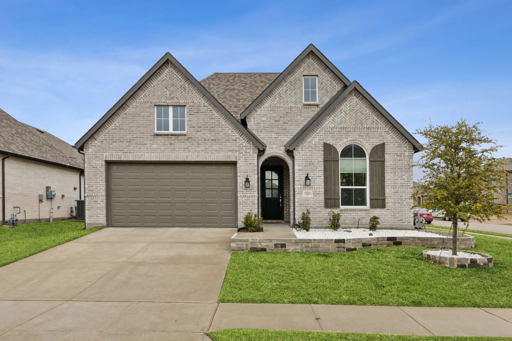 Brick exterior with an arched entry, two-car garage, and established landscaping
