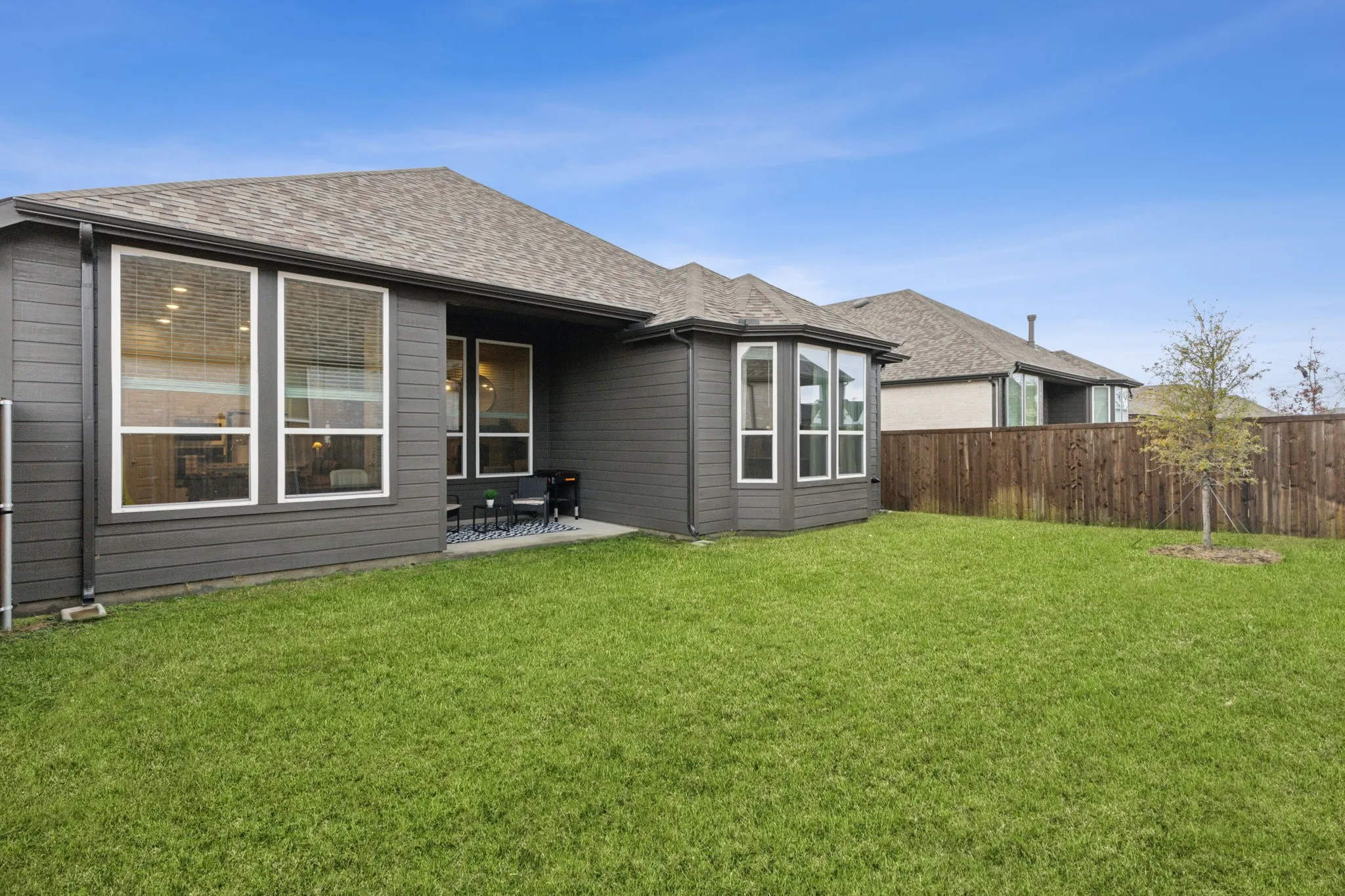Expansive backyard with a manicured lawn, full privacy fencing, and a concrete patio