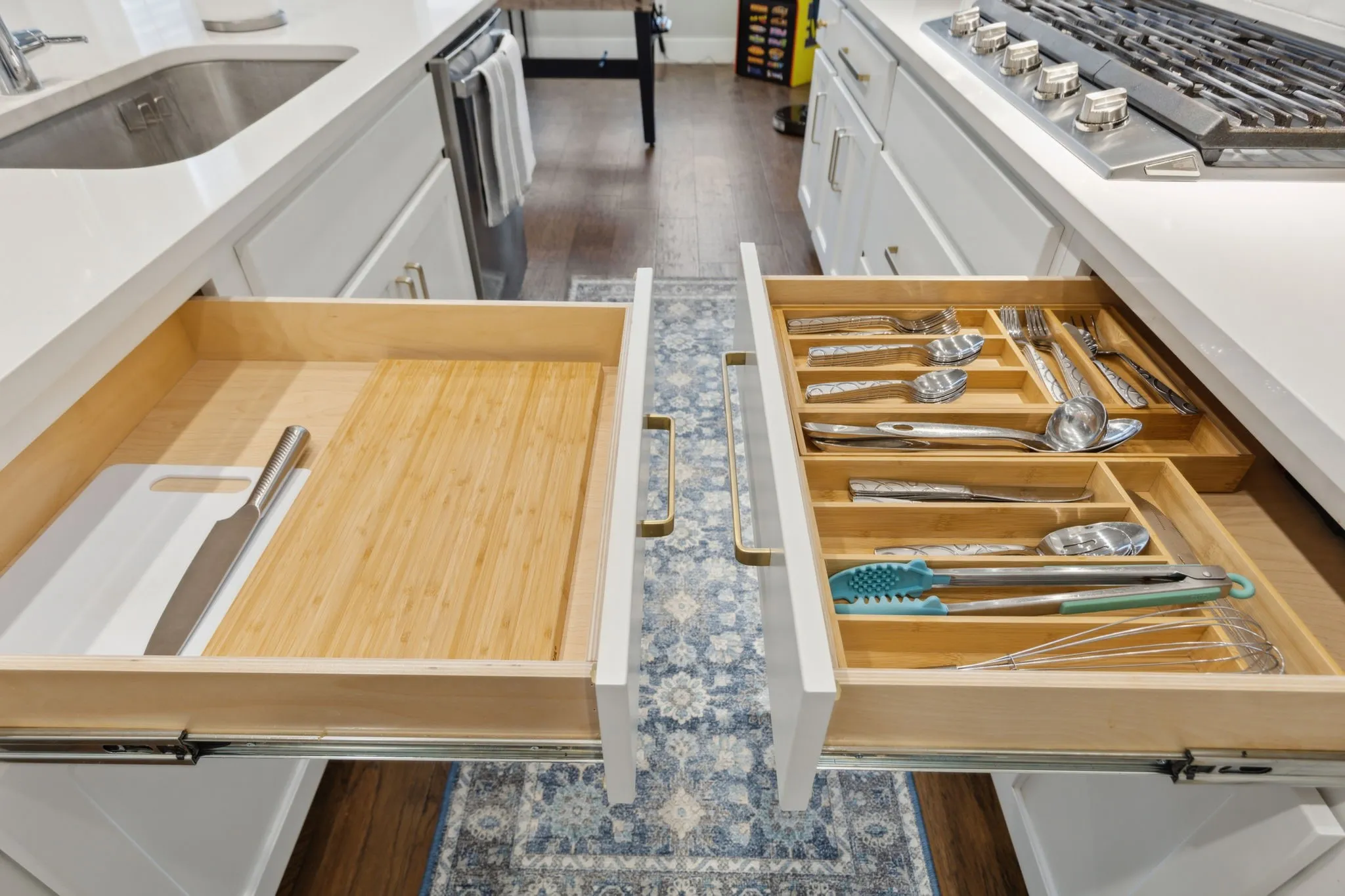 Built-in drawer organization, under-counter cabinetry, integrated cutting board storage, stainless steel sink, and gas range with griddle