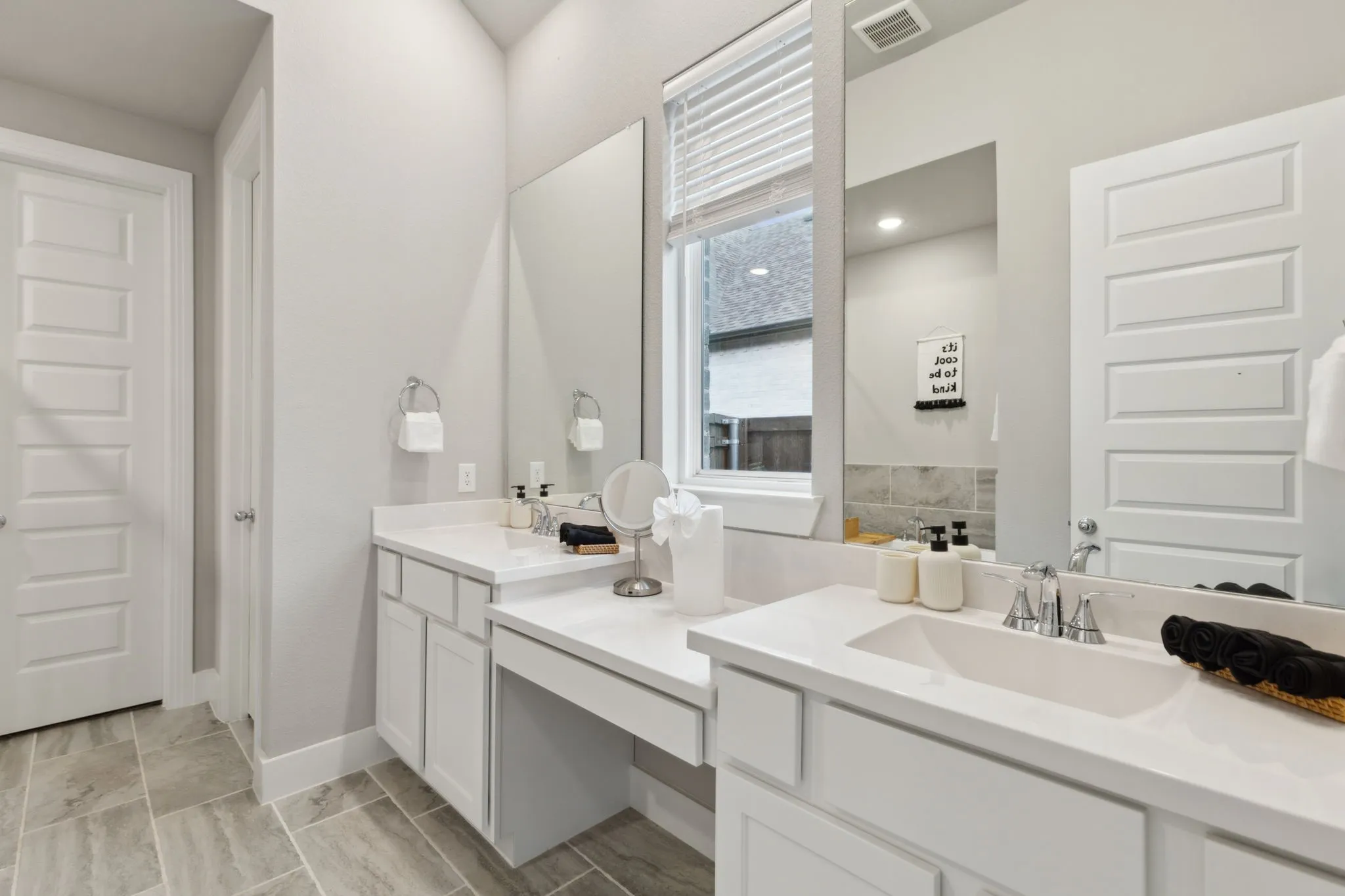Dual vanities with integrated sinks, white cabinetry, and light-toned countertops