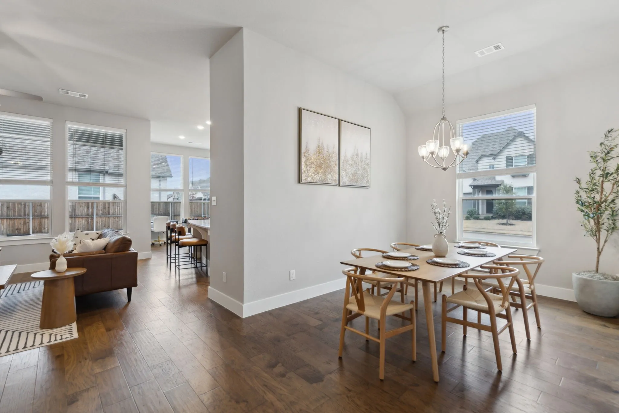 Expansive wood-finish flooring throughout, large windows with natural light, modern chandelier, recessed lighting, and crisp white trim
