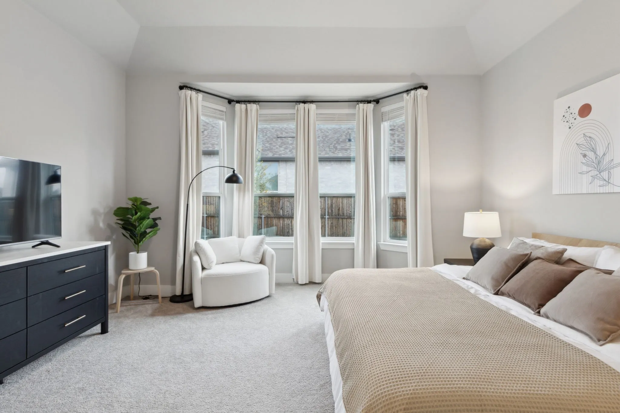 Bay window with curtain rods, light-toned walls, and vaulted ceiling