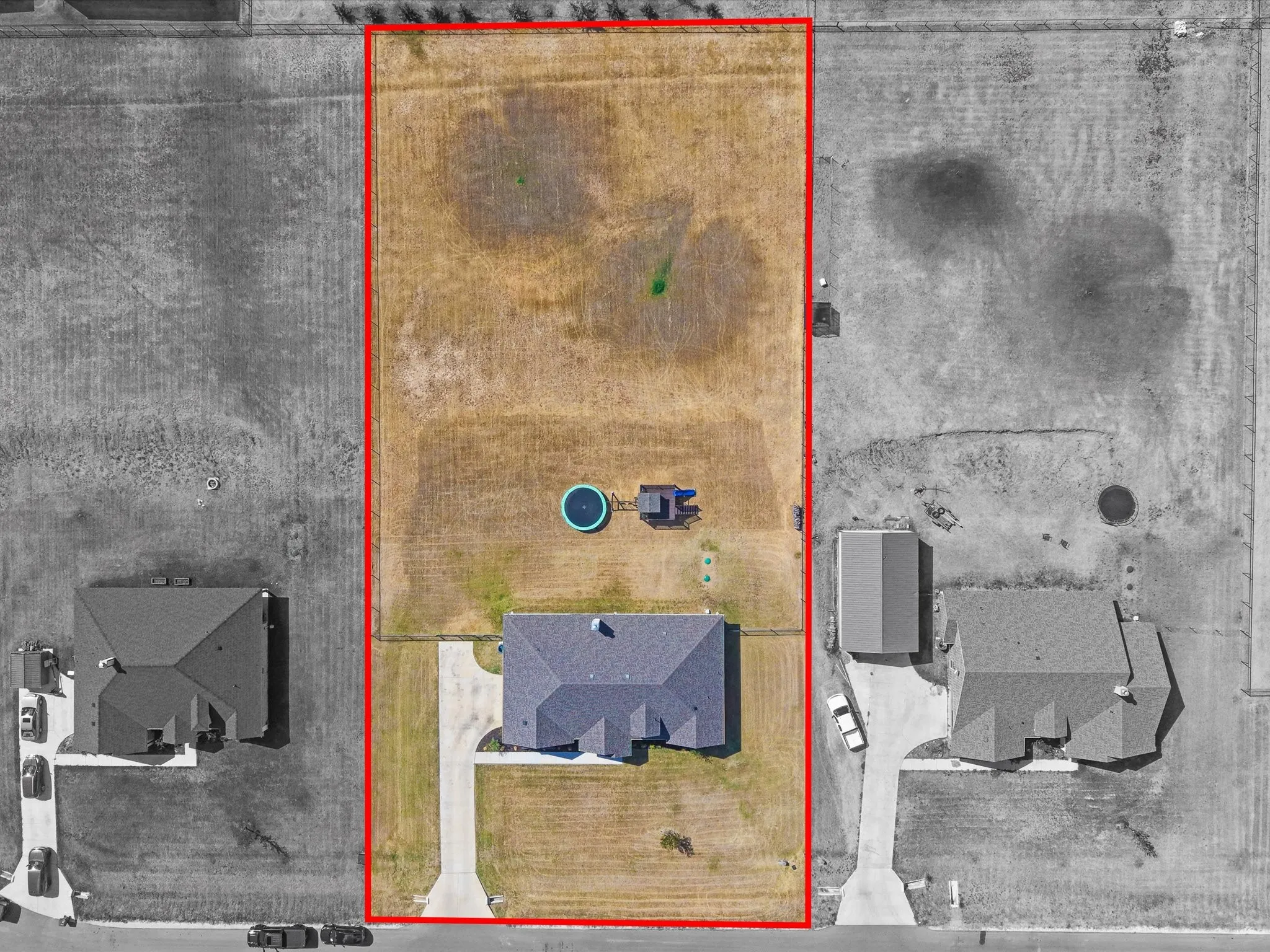 Expansive lot featuring a single-story residence with a dark-toned roof and an elongated driveway