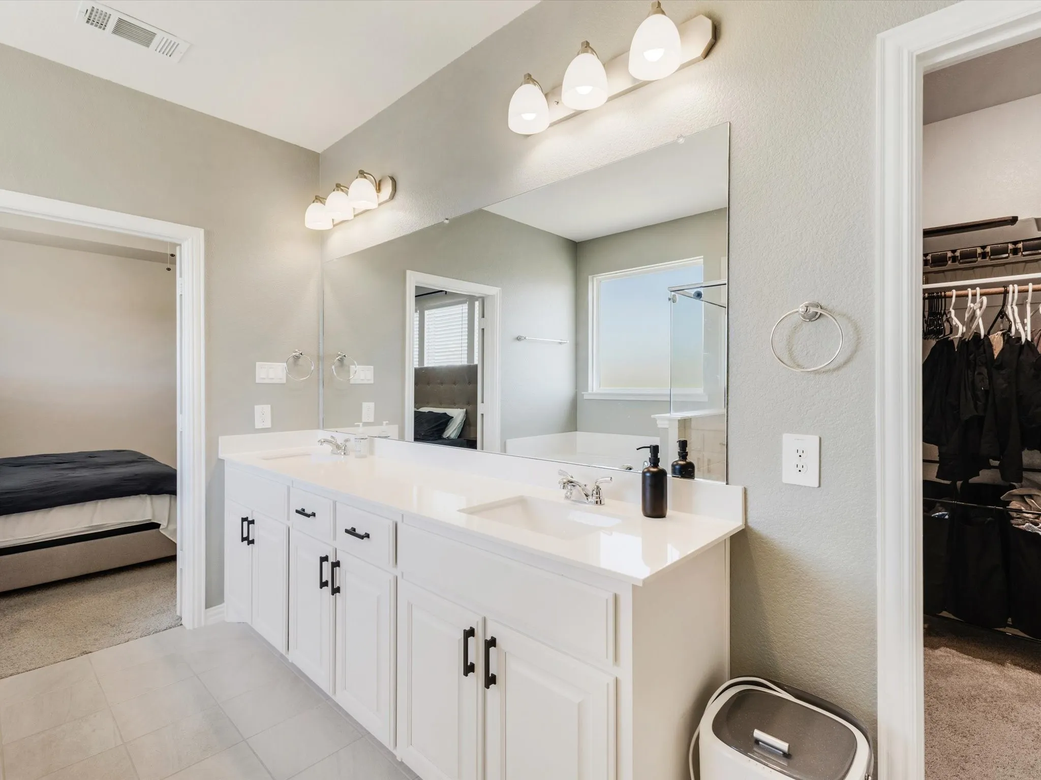 Dual vanity with white cabinetry, matte black hardware, and light-toned countertops