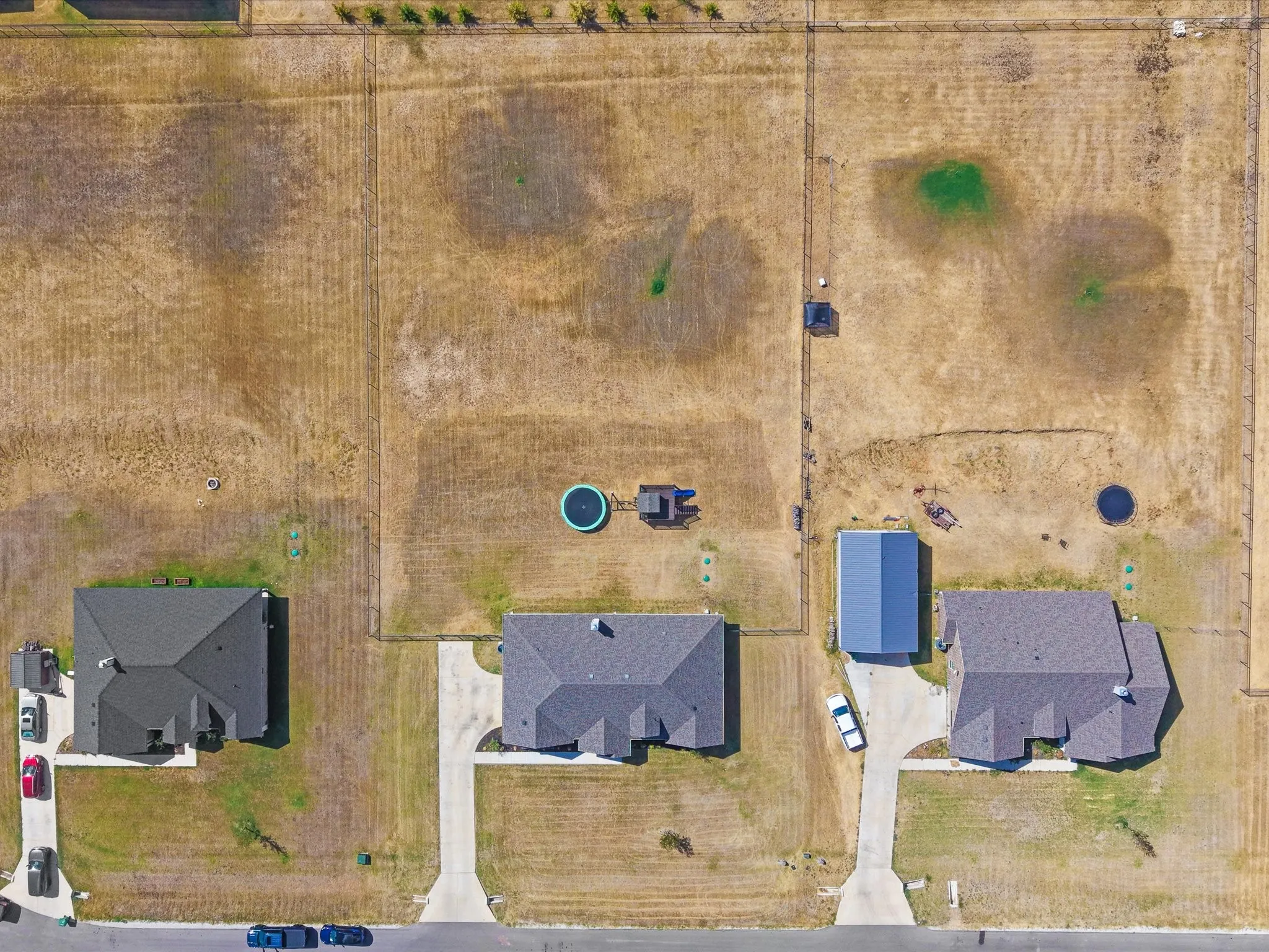 Two single-story residences with dark shingle roofs, each featuring a private driveway, set on expansive land