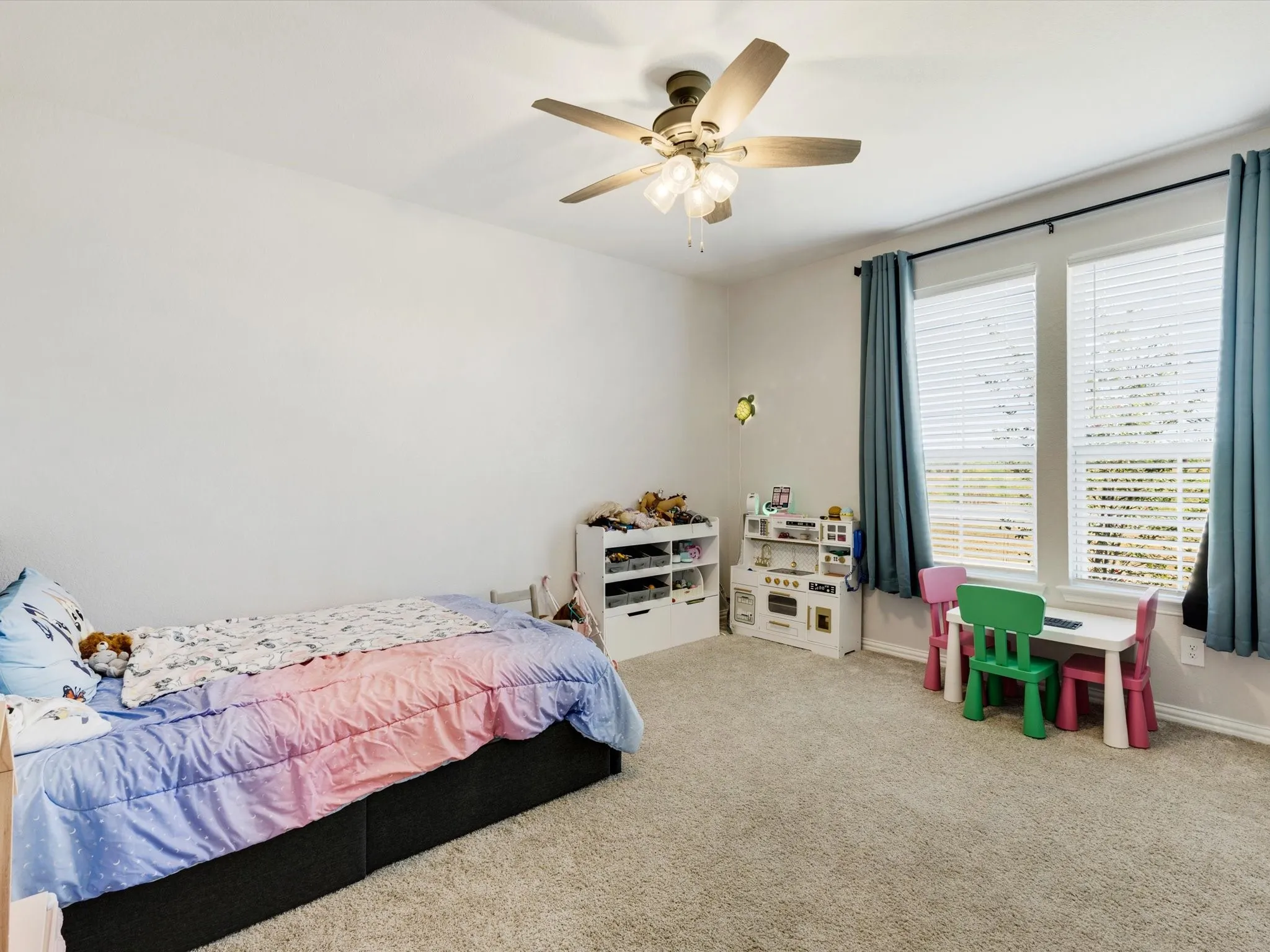 Textured carpeting, ceiling fan with integrated lighting, and a white paneled door
