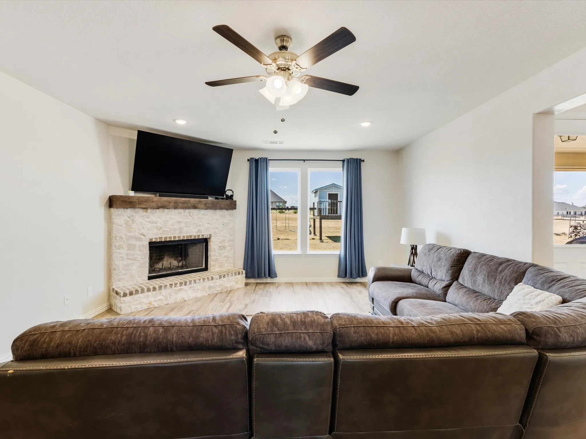 Corner fireplace featuring a stone surround and wood mantel