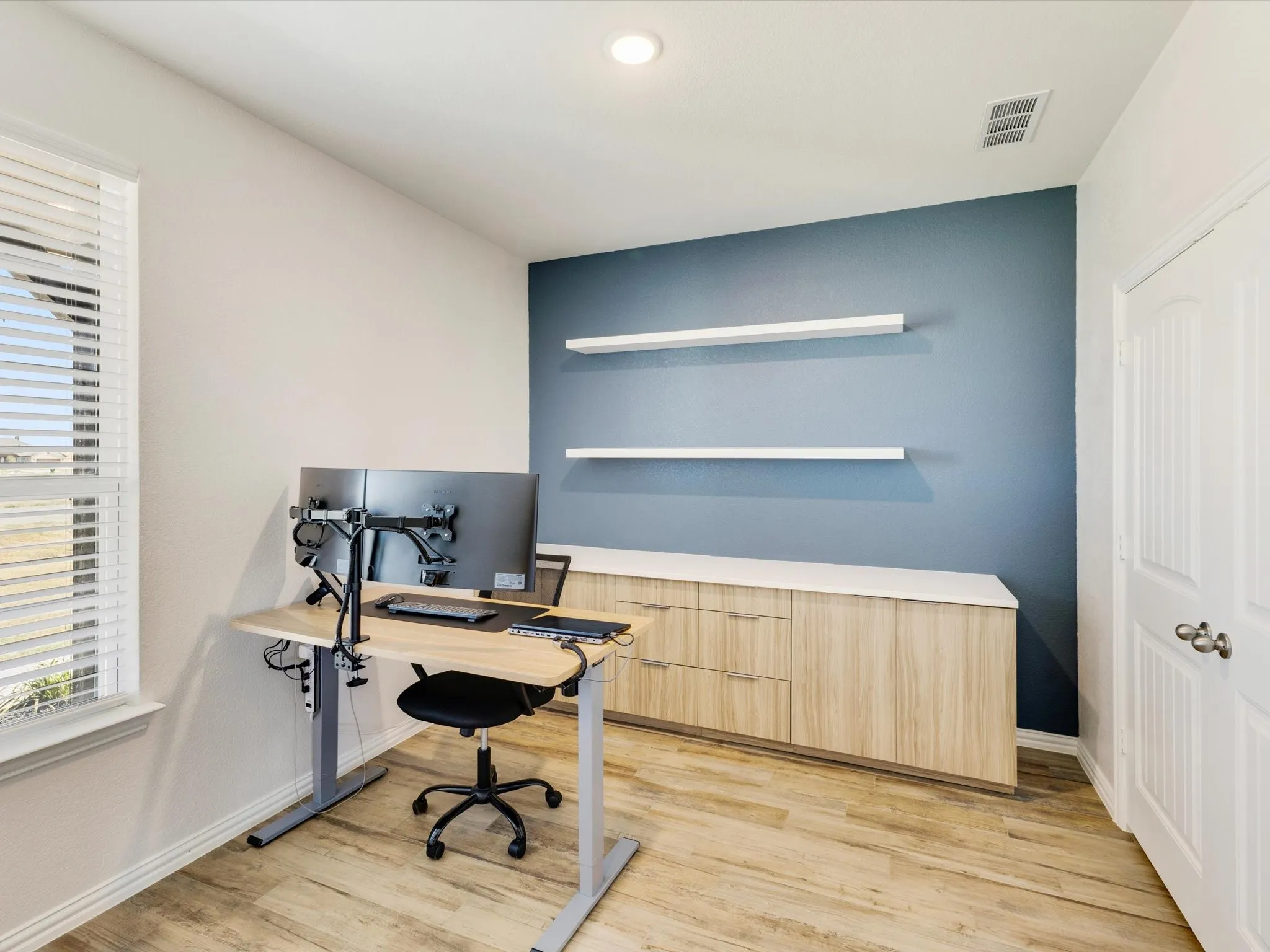 Wood-finish flooring, built-in cabinetry with a light-toned countertop, and floating wall shelves
