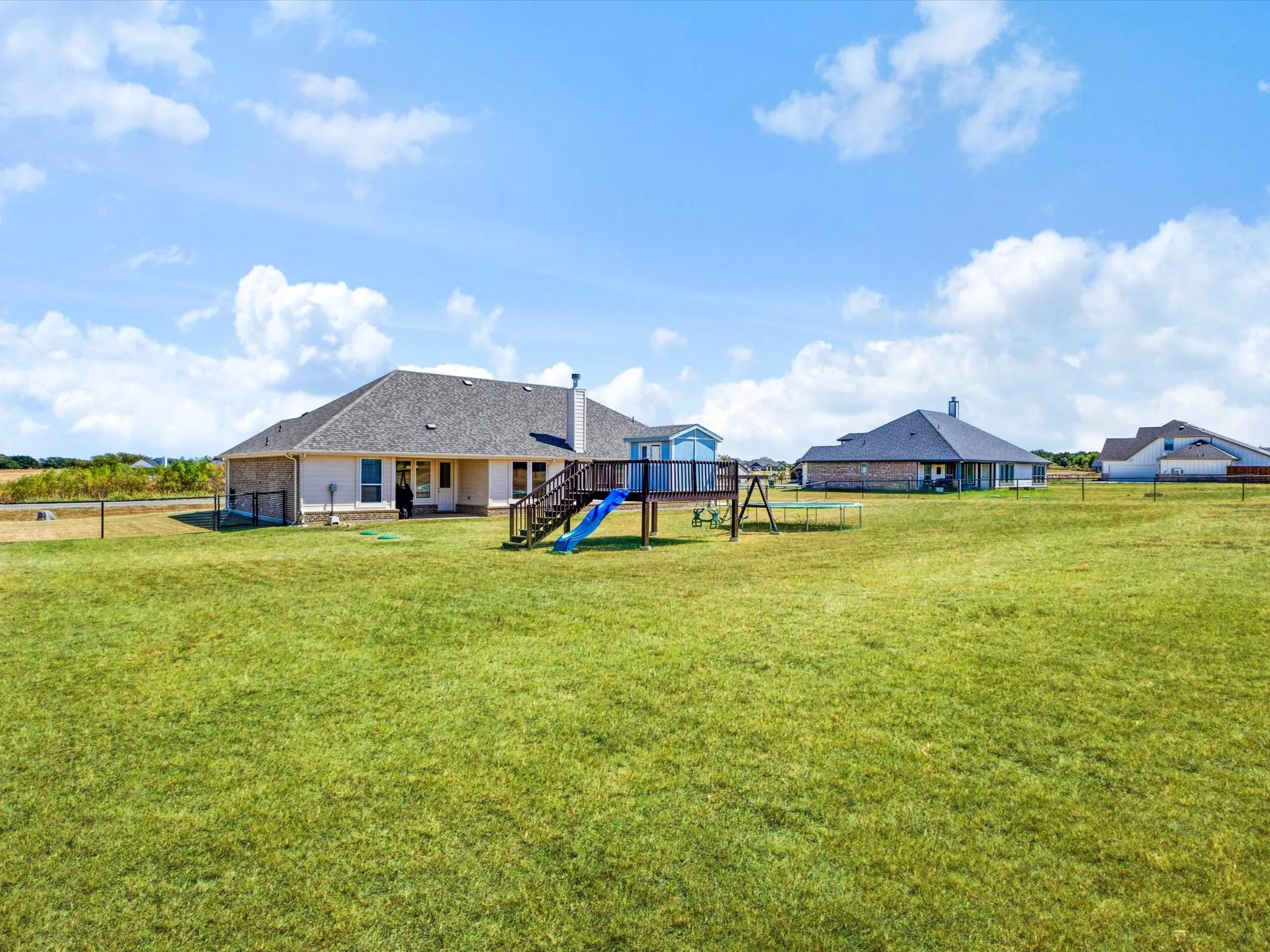 Expansive backyard with a wooden deck and staircase