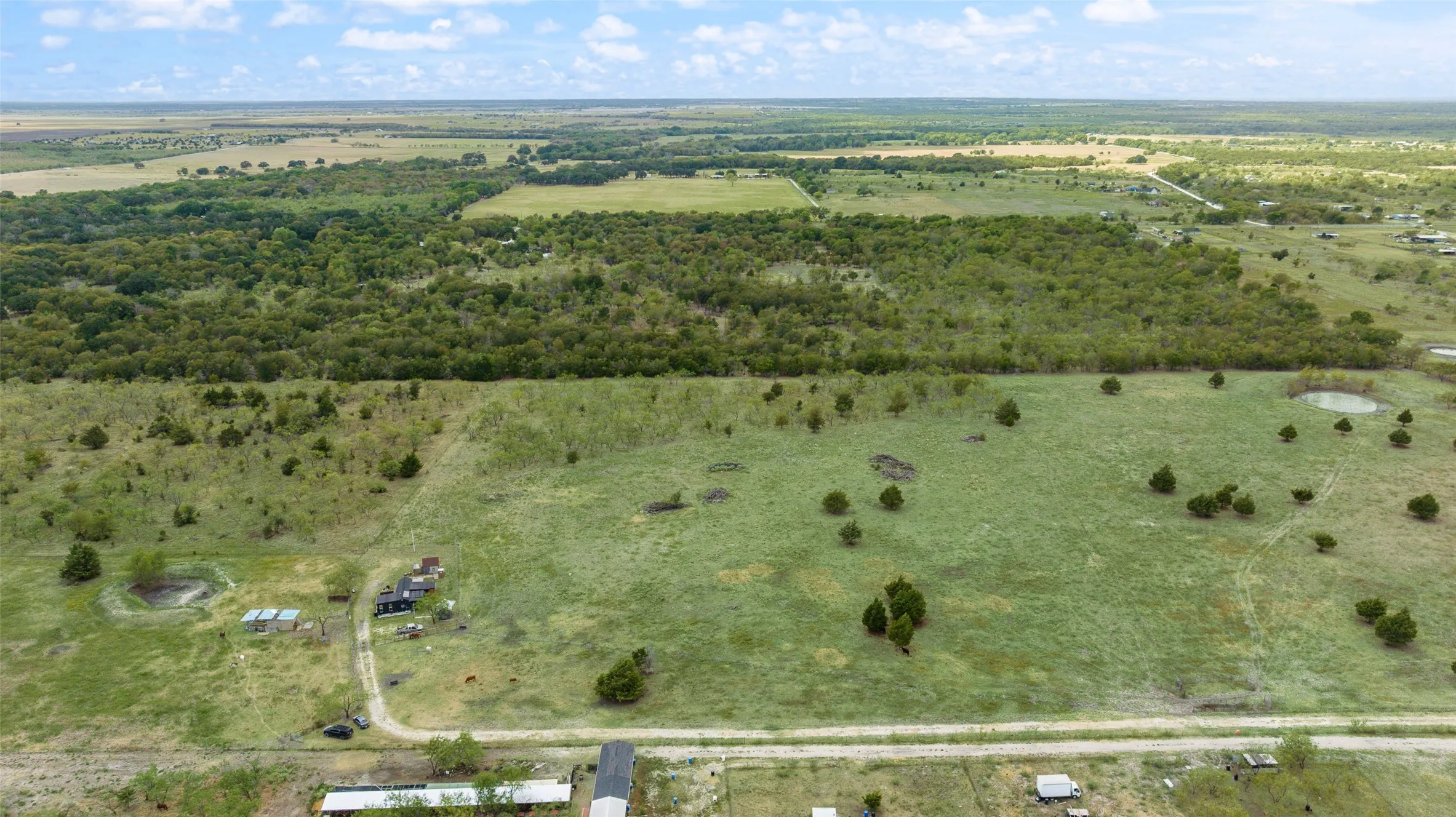 Expansive undeveloped land featuring a combination of open fields and mature tree lines