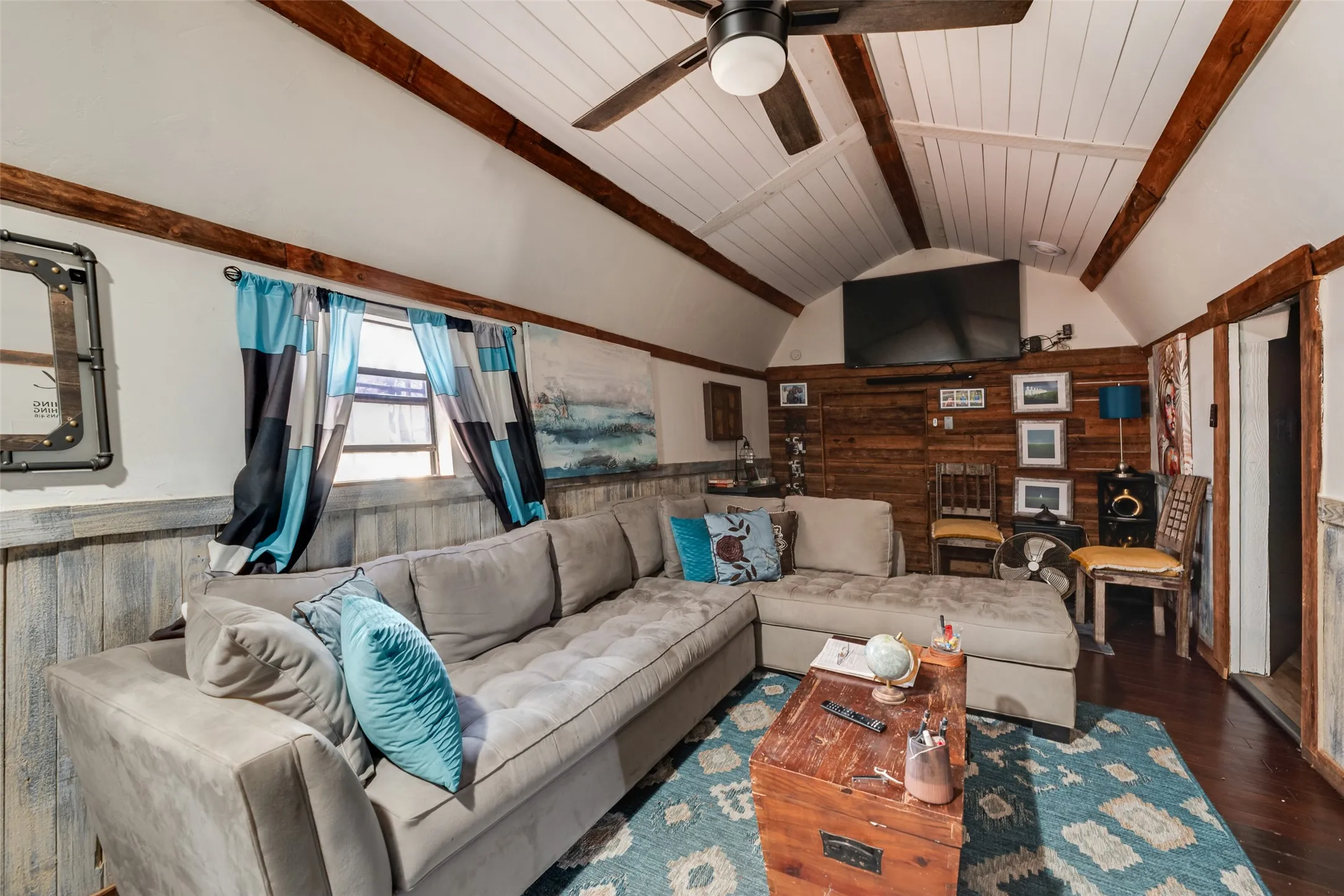Vaulted ceilings with exposed wood beams, wood-plank accent wall, and wood-finish flooring
