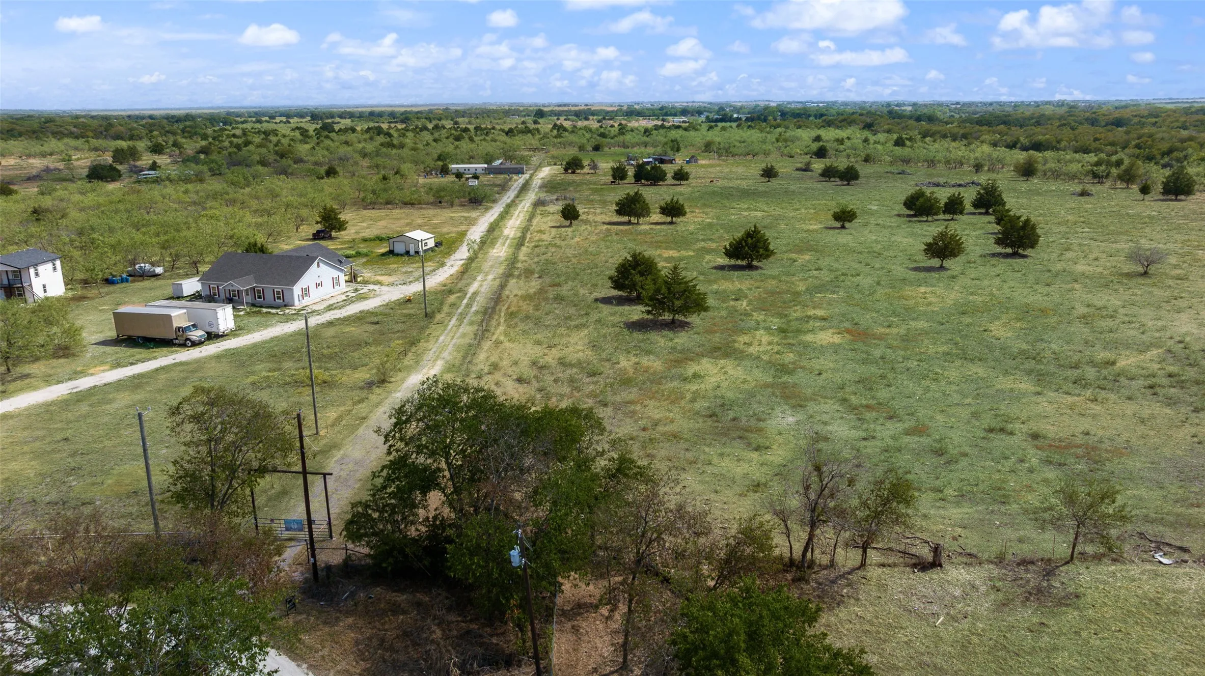 Expansive rural property featuring an unpaved private road and scattered mature trees