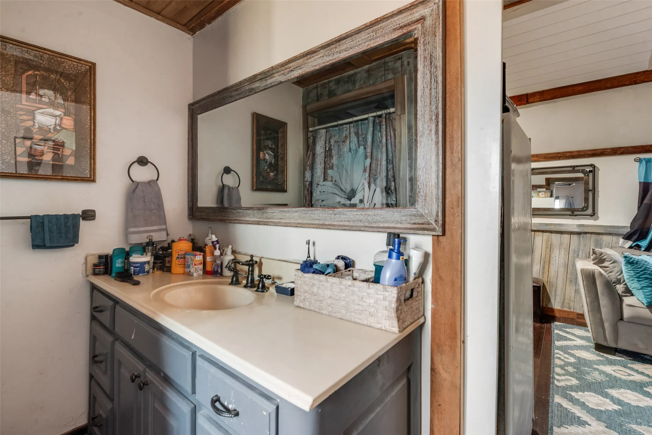 Bathroom featuring a single vanity with an integrated sink, a dark-finish faucet, and a large framed mirror