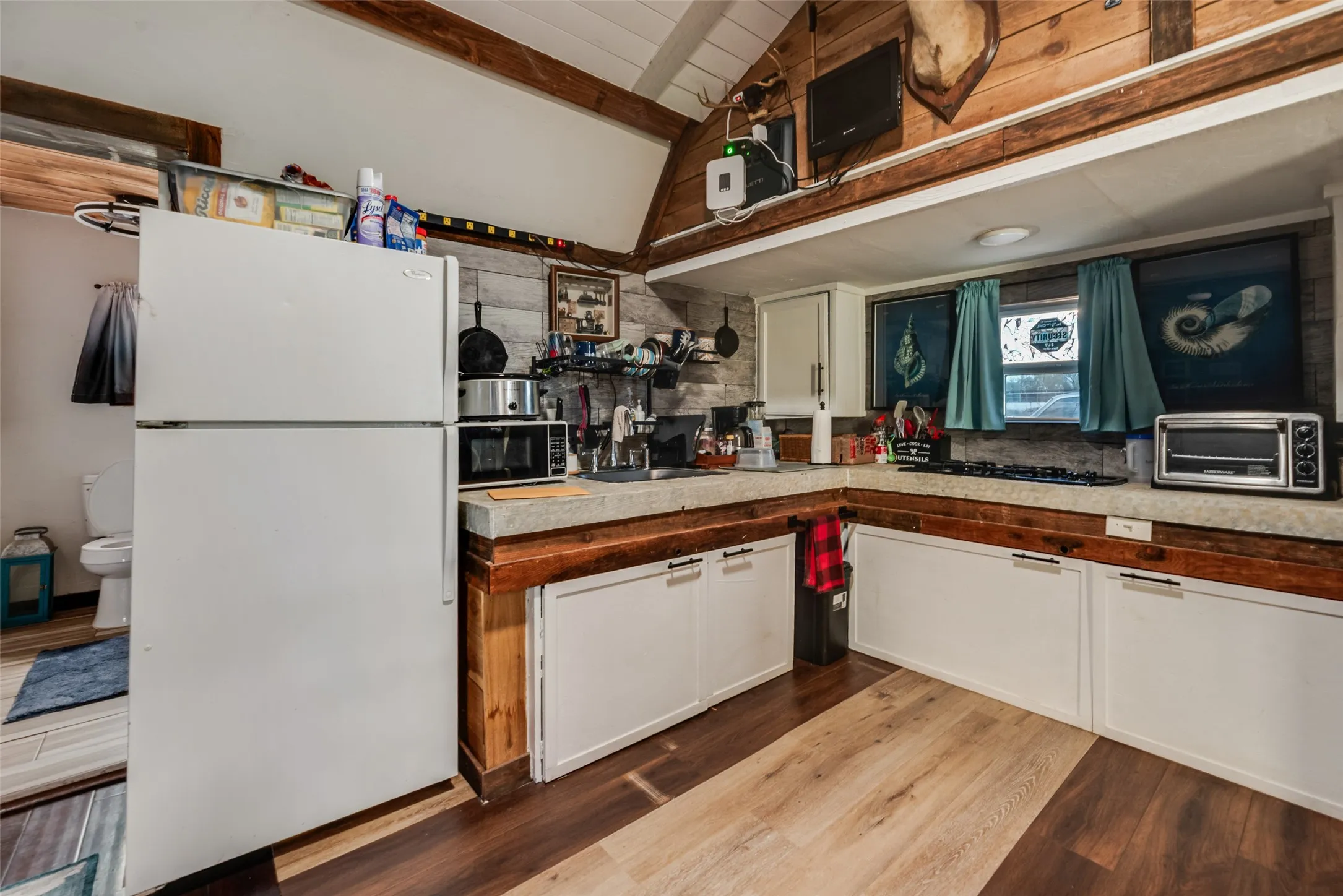 Wood-finish flooring with dual tones, white base cabinets, and a durable countertop