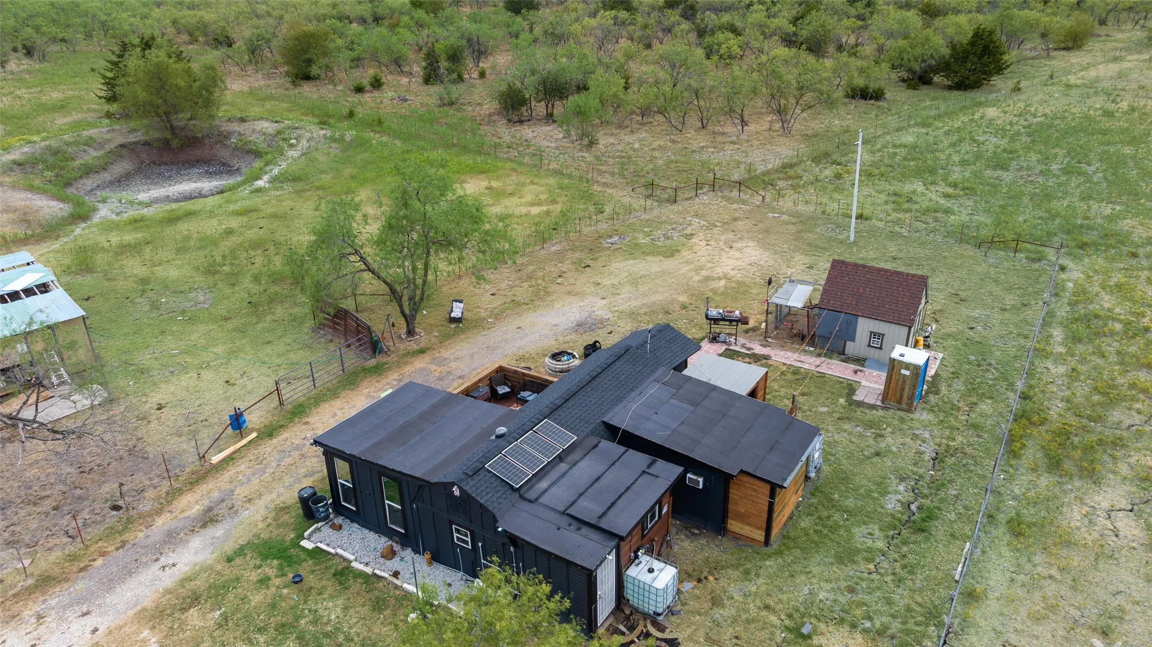 Property featuring multiple structures, solar panels, and surrounding natural landscape
