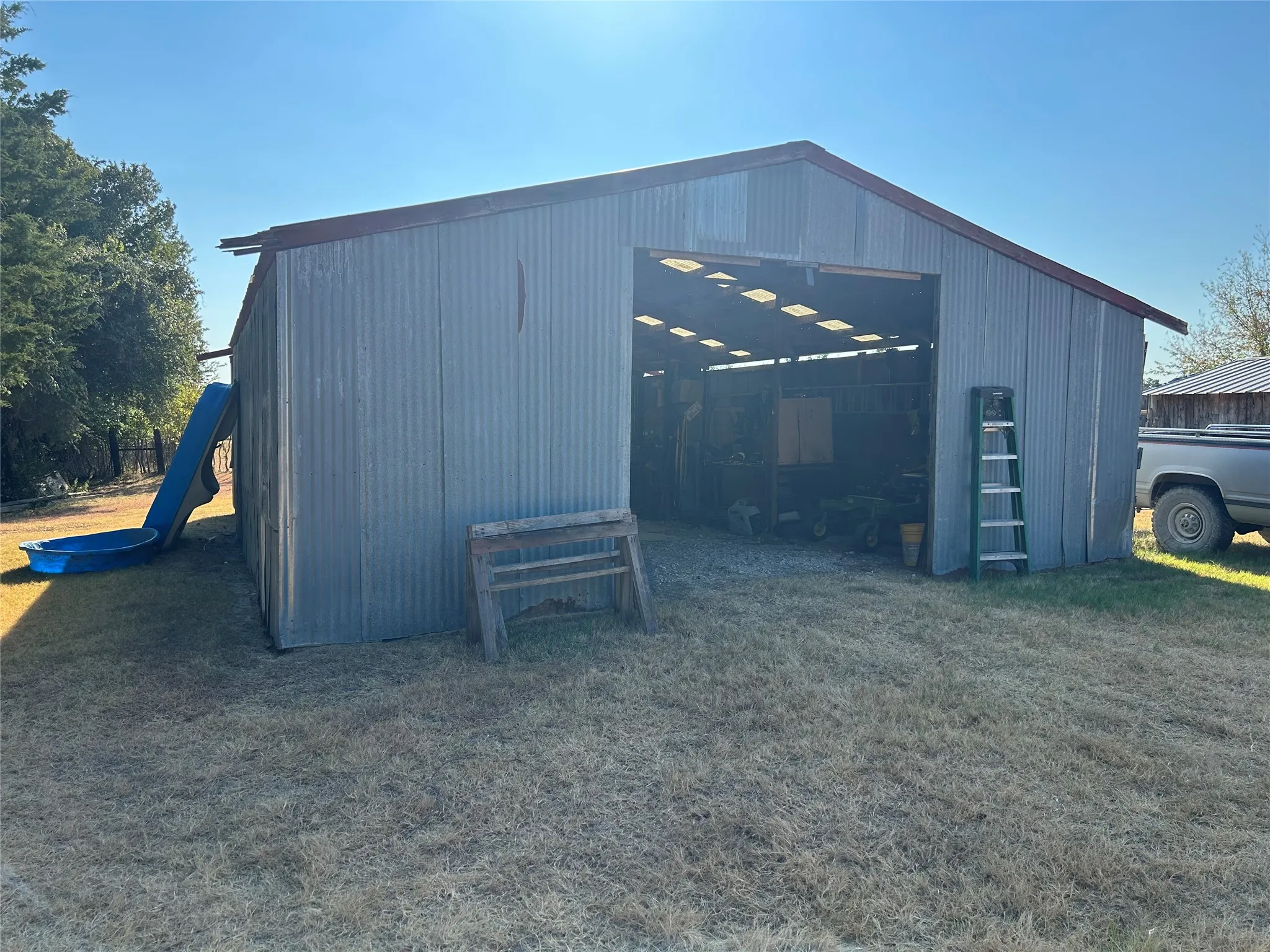 Corrugated metal building with an open bay entrance and a red trim roof