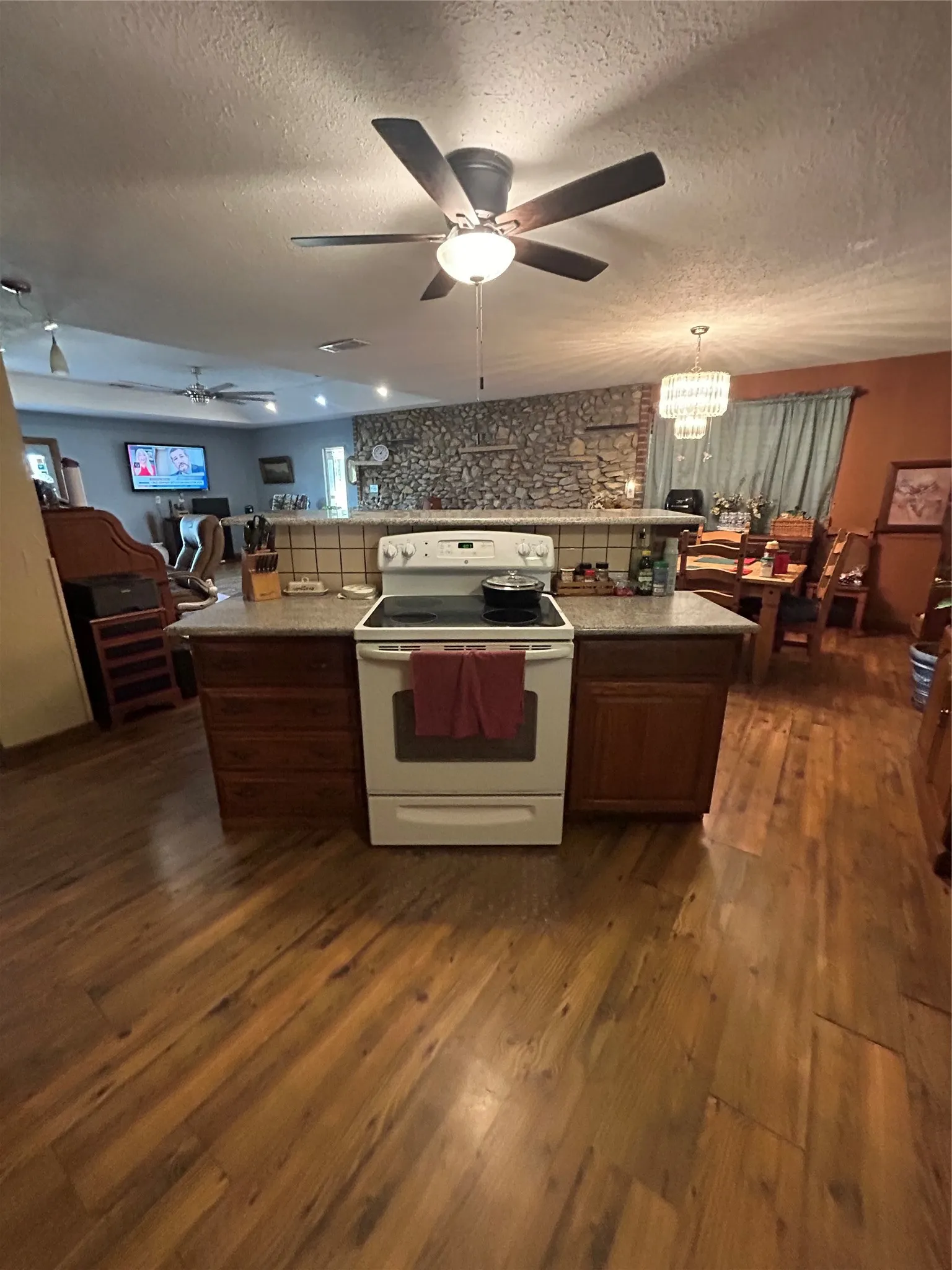 Wood-finish flooring throughout, with a built-in range on an island featuring wood cabinetry
