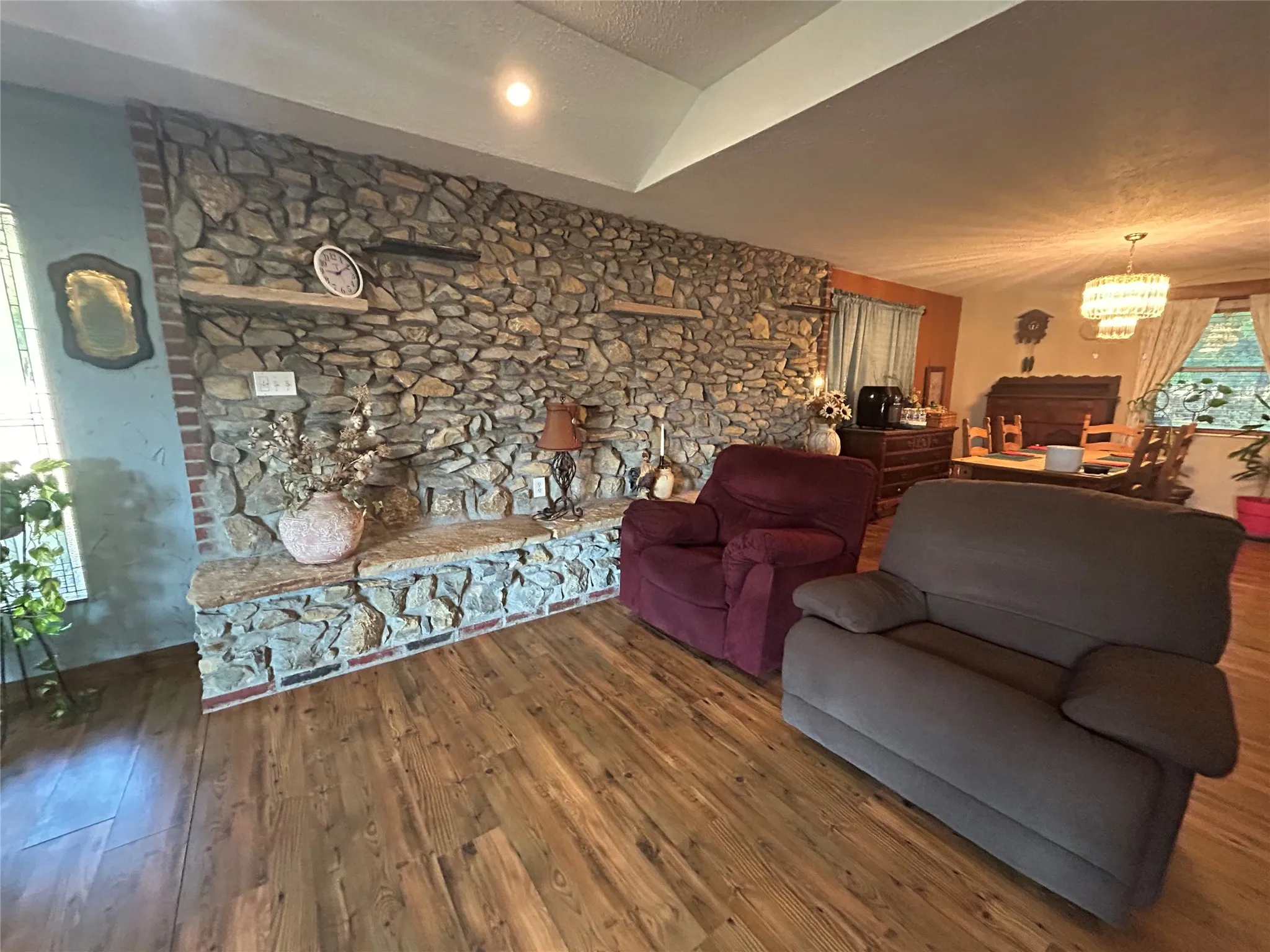 Stone-clad accent wall with built-in shelving, granite-finish hearth, and wood-finish flooring