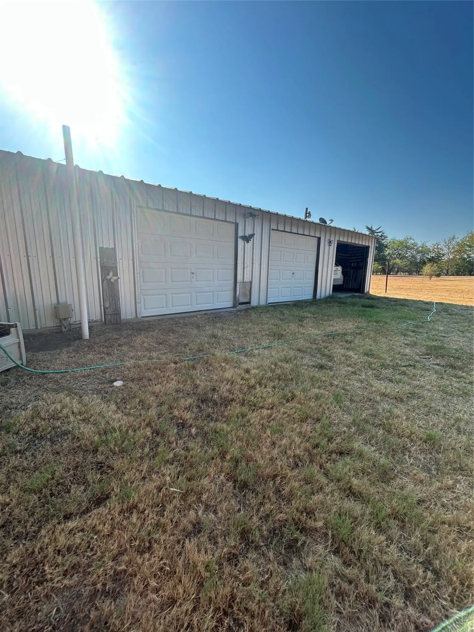Corrugated metal structure featuring two roll-up garage doors and an open bay