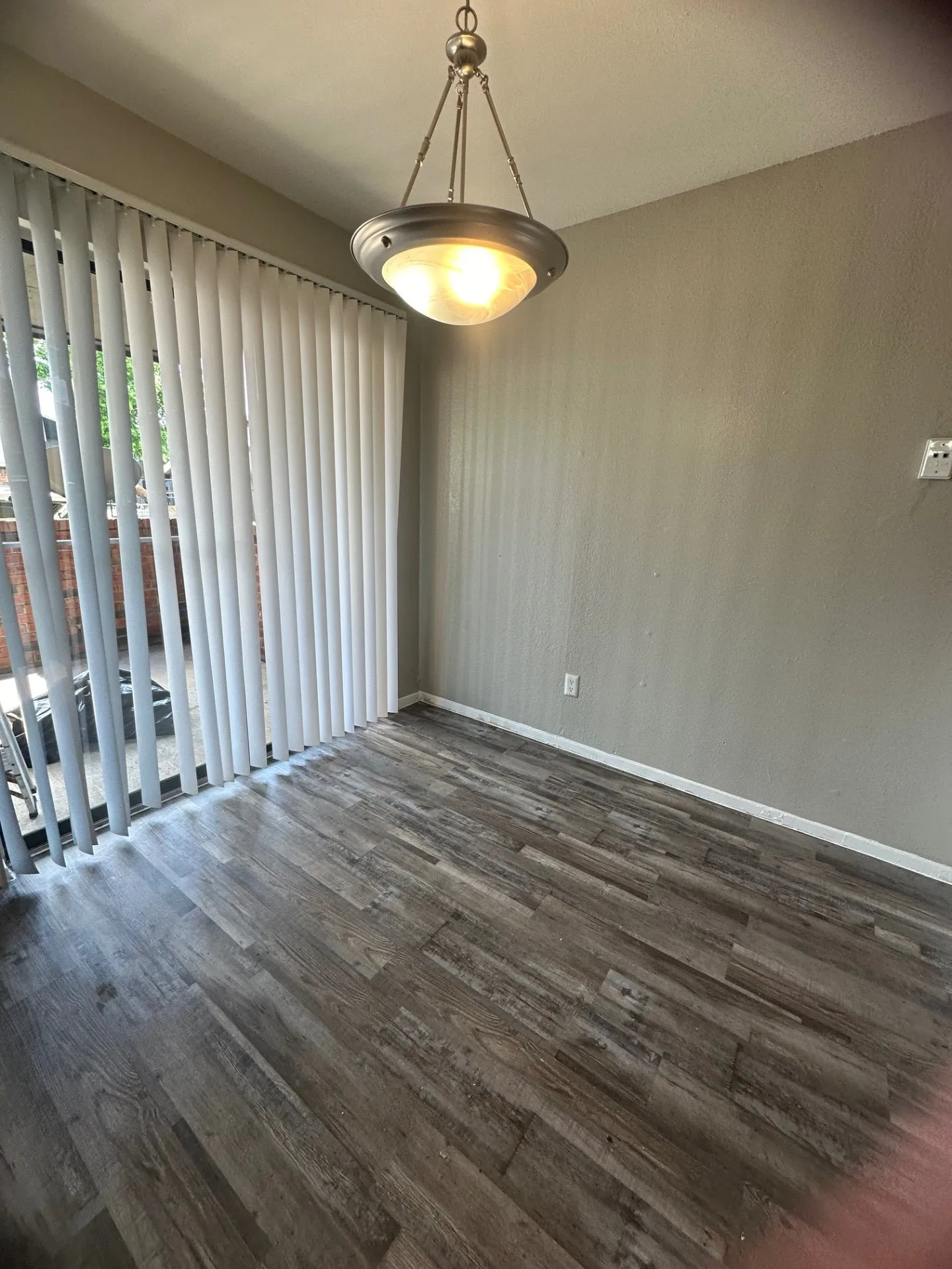 Wood-finish flooring with vertical blinds and a ceiling-mounted light fixture