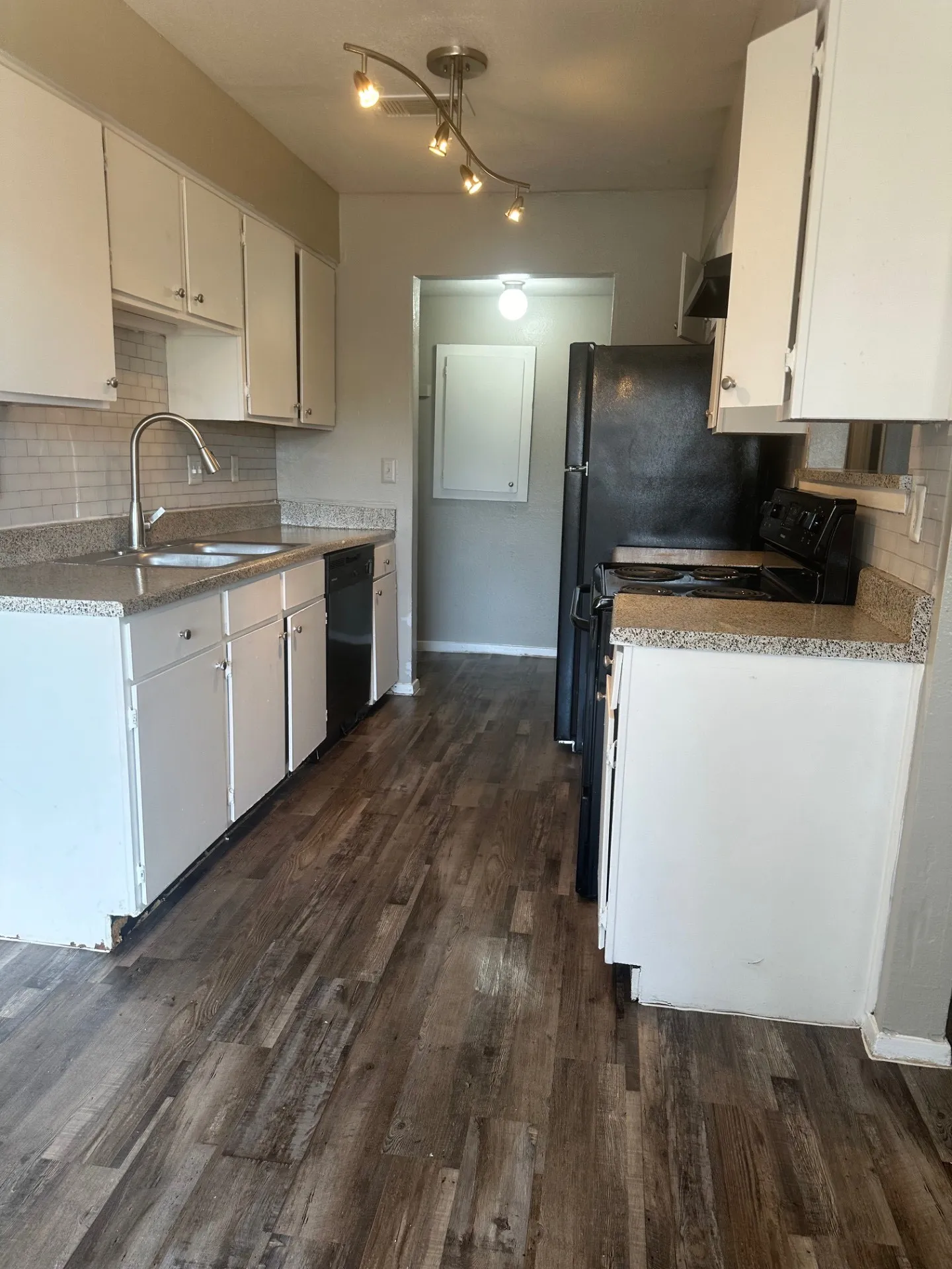 Kitchen featuring wood-finish flooring, white cabinetry, a stainless steel sink with a gooseneck faucet, light-toned countertops, and a subway tile backsplash