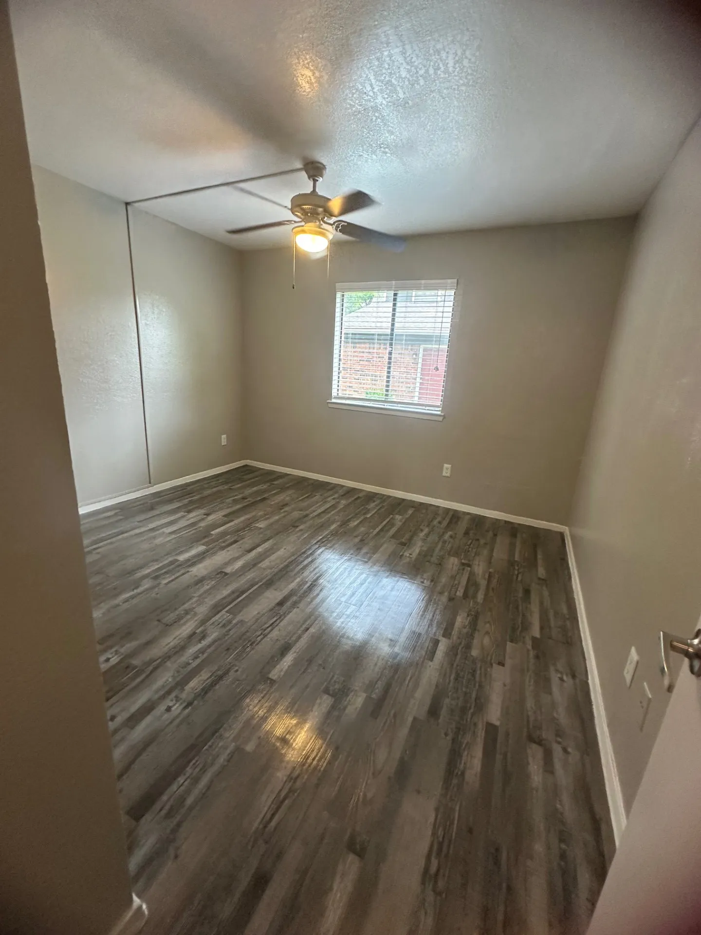 Wood-finish flooring, ceiling fan with integrated lighting, window with blinds, and neutral wall tones