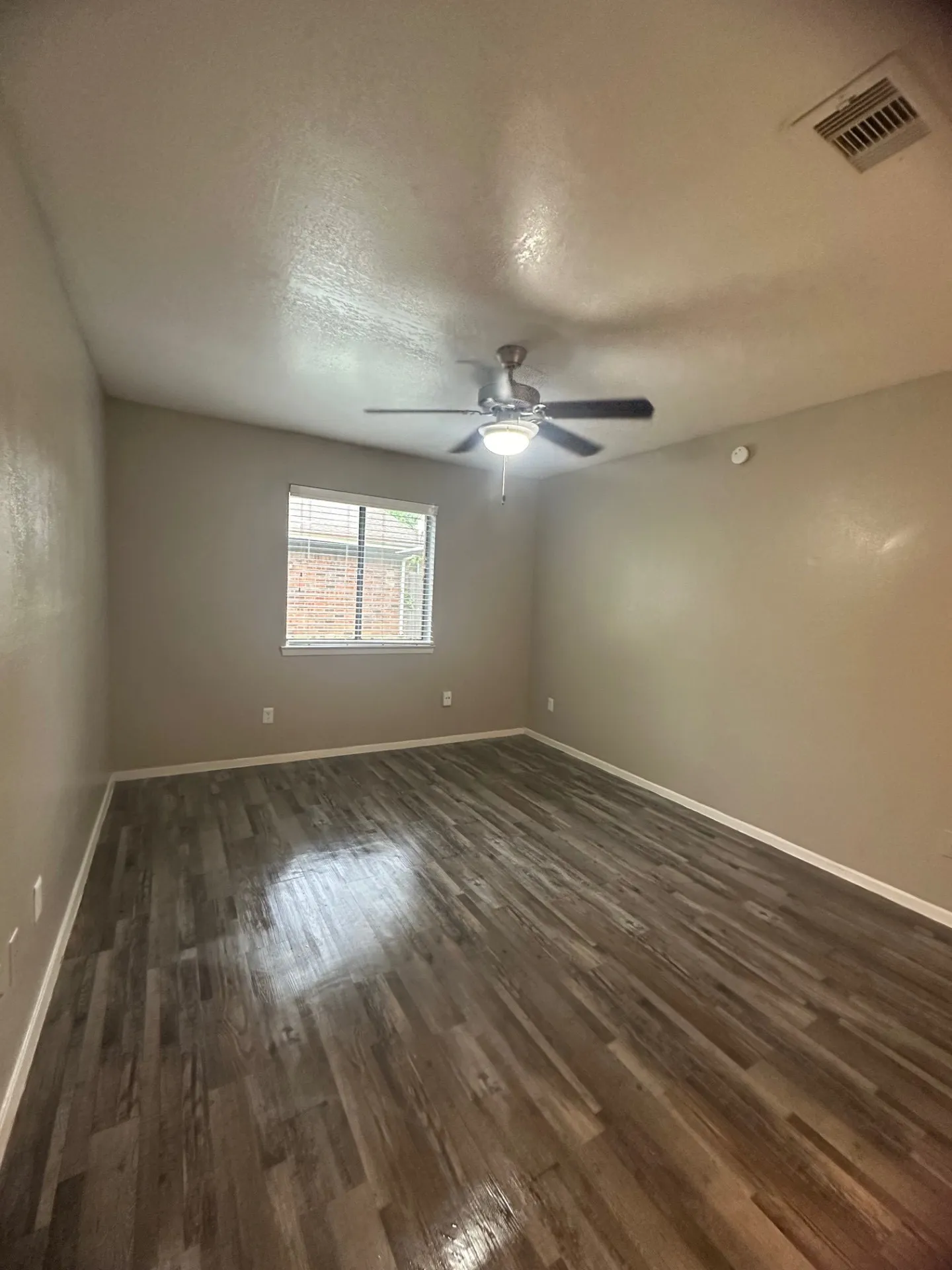 Wood-finish flooring with a ceiling fan light fixture and a single window