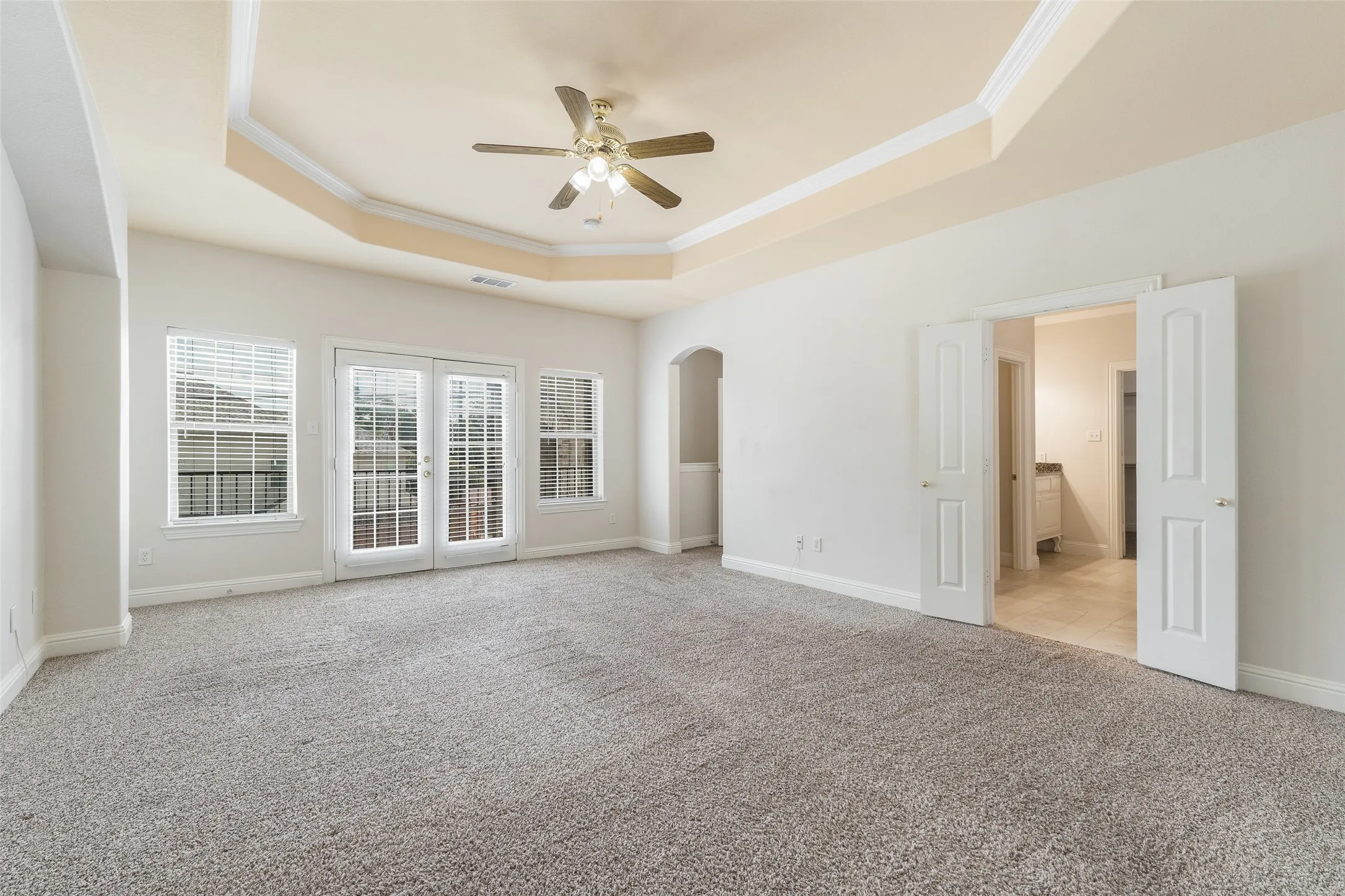 Tray ceiling with crown molding and ceiling fan, carpeted flooring, French doors with side windows, and double interior doors