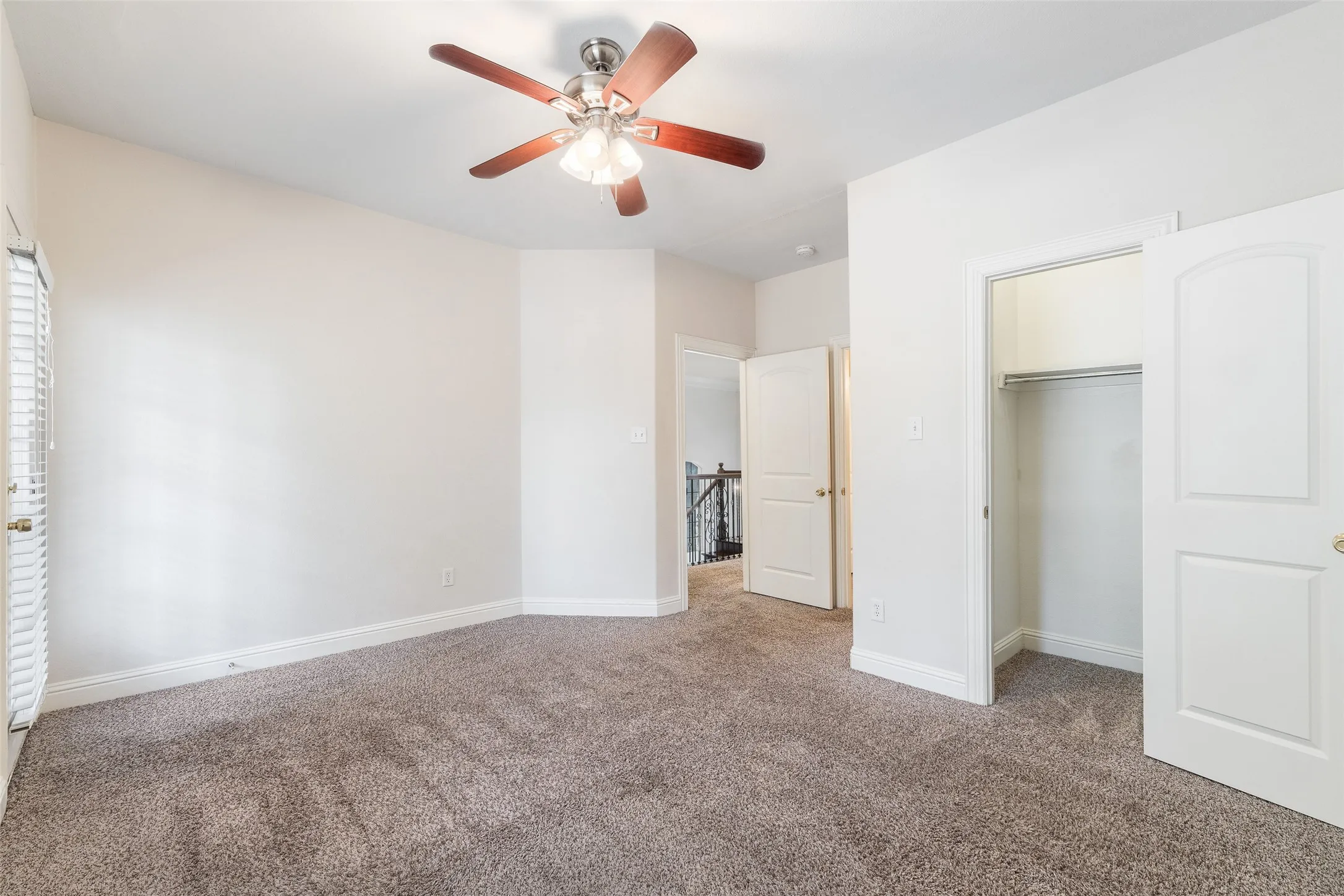 Plush carpeting, ceiling fan with light fixture, white interior doors, and a closet with hanging rod