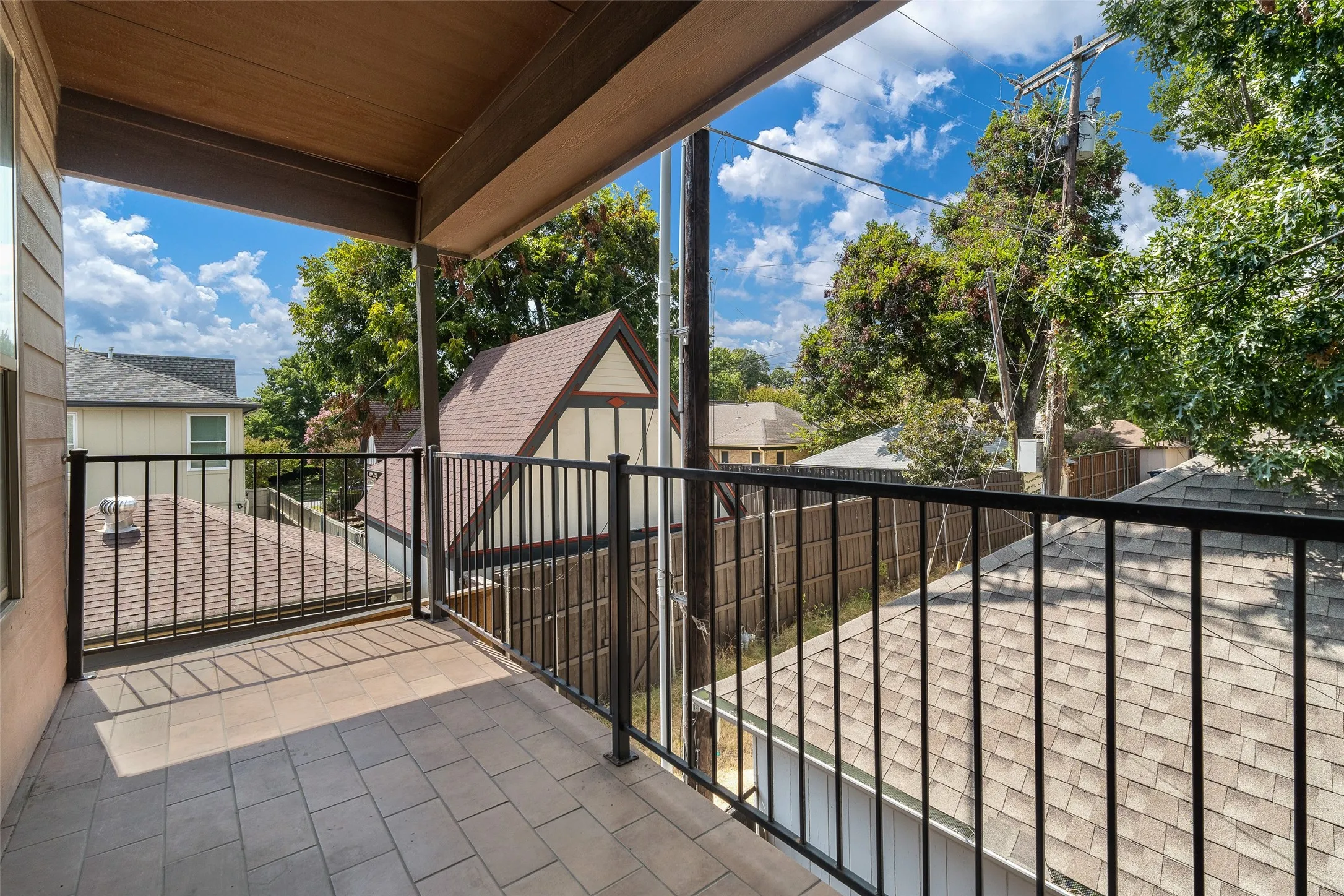 Covered balcony featuring tile flooring and black metal railings