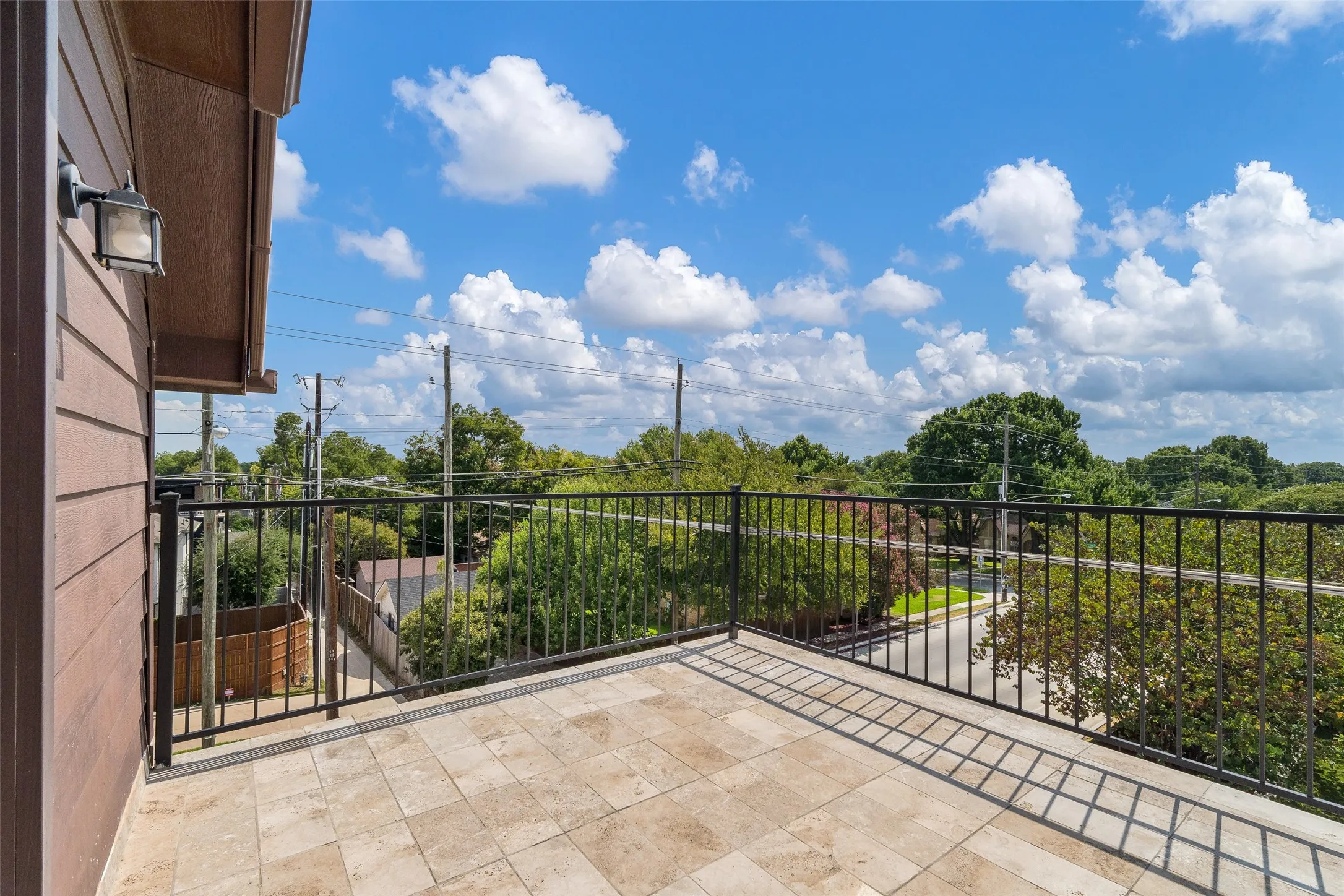 Terrace with stone tile flooring, black metal railing, and exterior wall lighting