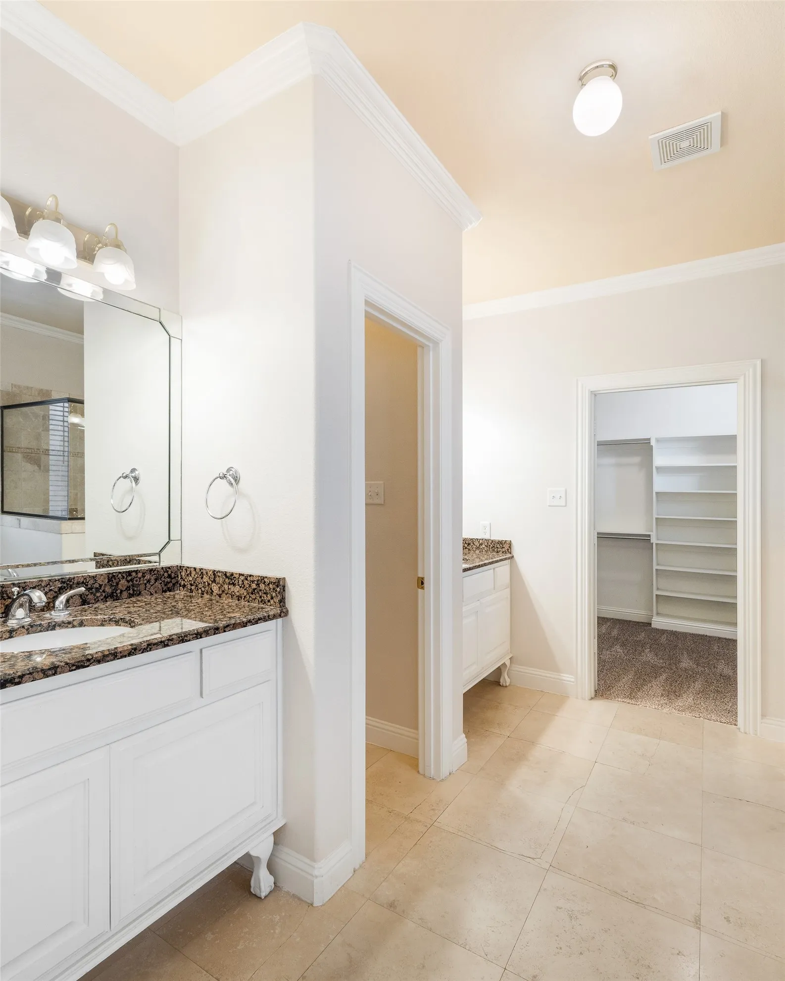 Dual white vanities with integrated sinks and granite countertops, tile flooring, and crown molding