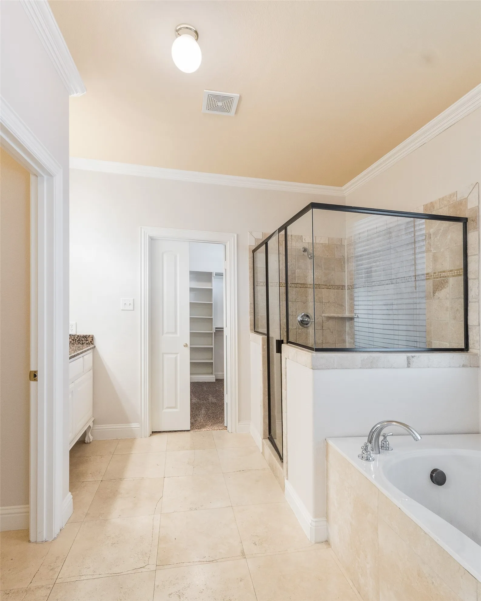 Spacious bathroom featuring a built-in soaking tub, glass-enclosed shower with tile surround, a vanity with a stone countertop, and tile flooring
