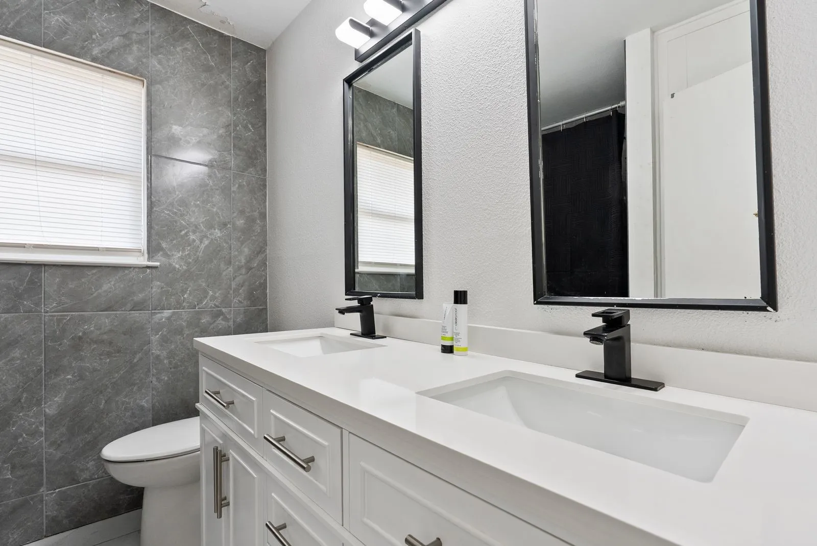 Dual vanity with white shaker-style cabinetry, white countertops, and matte black fixtures