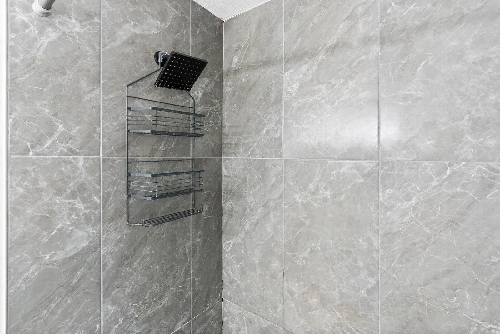 Large-format shower tiles with a light grey finish and subtle veining