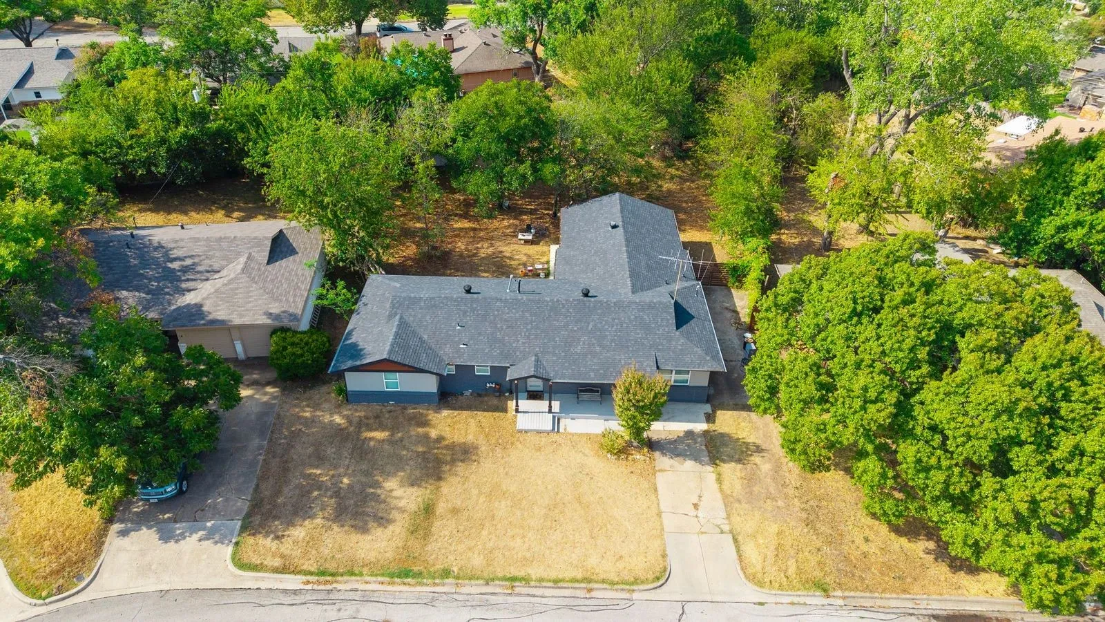 Single-story residence with a dark gray roof, light gray exterior siding, and a concrete driveway
