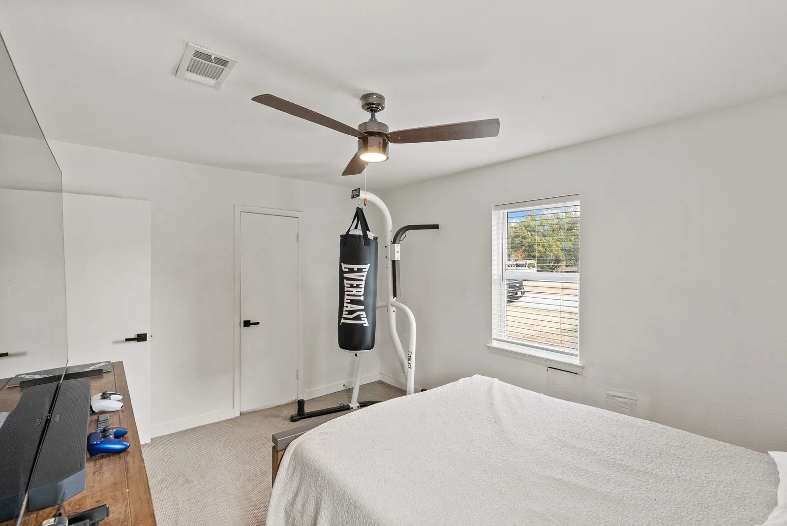 White walls and ceiling, ceiling fan with integrated lighting, two white panel doors with black hardware, and a window with blinds