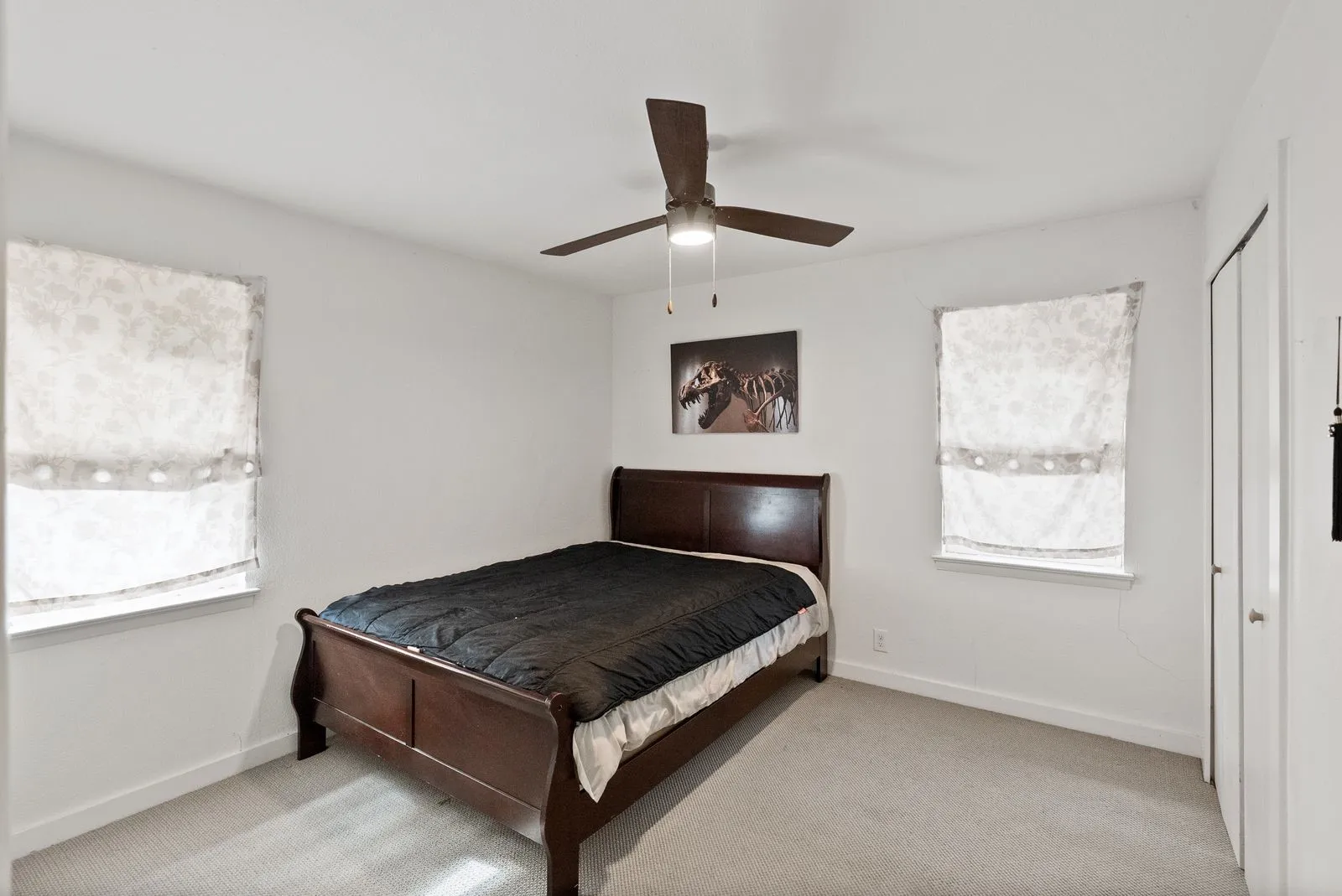 Recessed windows with window coverings, light-colored carpeting, a ceiling fan with integrated lighting, and a closet with bifold doors