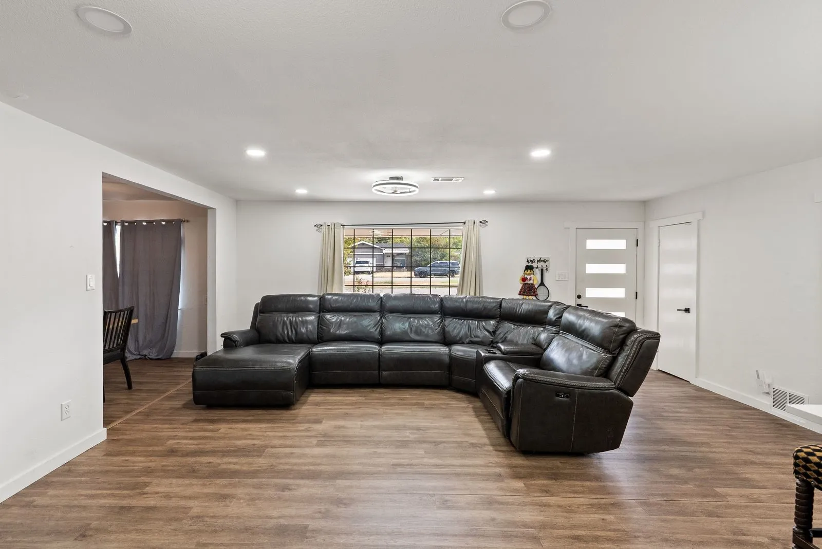 Wood-finish flooring, recessed ceiling lighting, a modern ceiling light fixture, and white interior doors