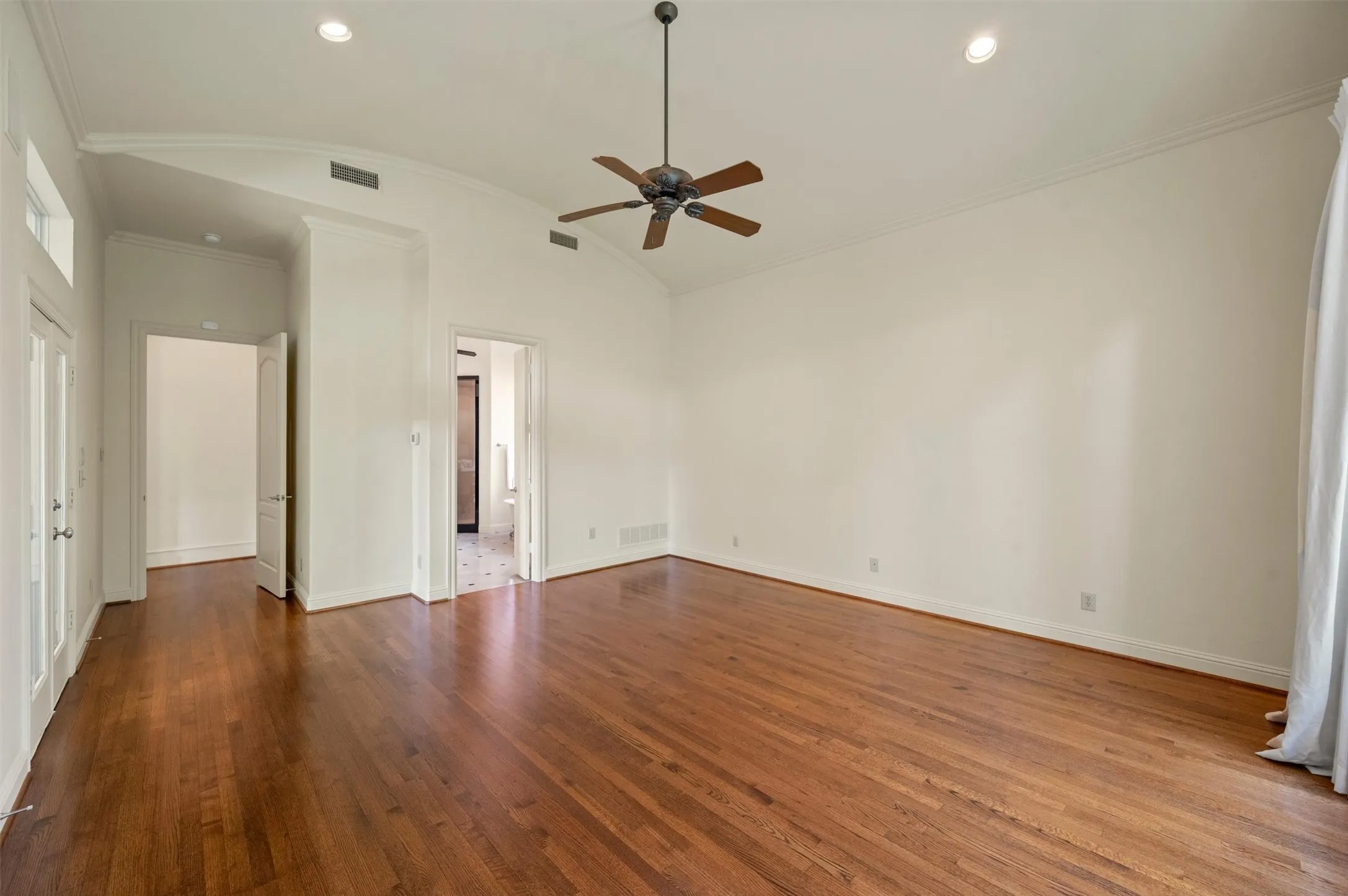 Wood floors adorn the primary suite. Notice the curved ceiling treatment, a very custom feature.