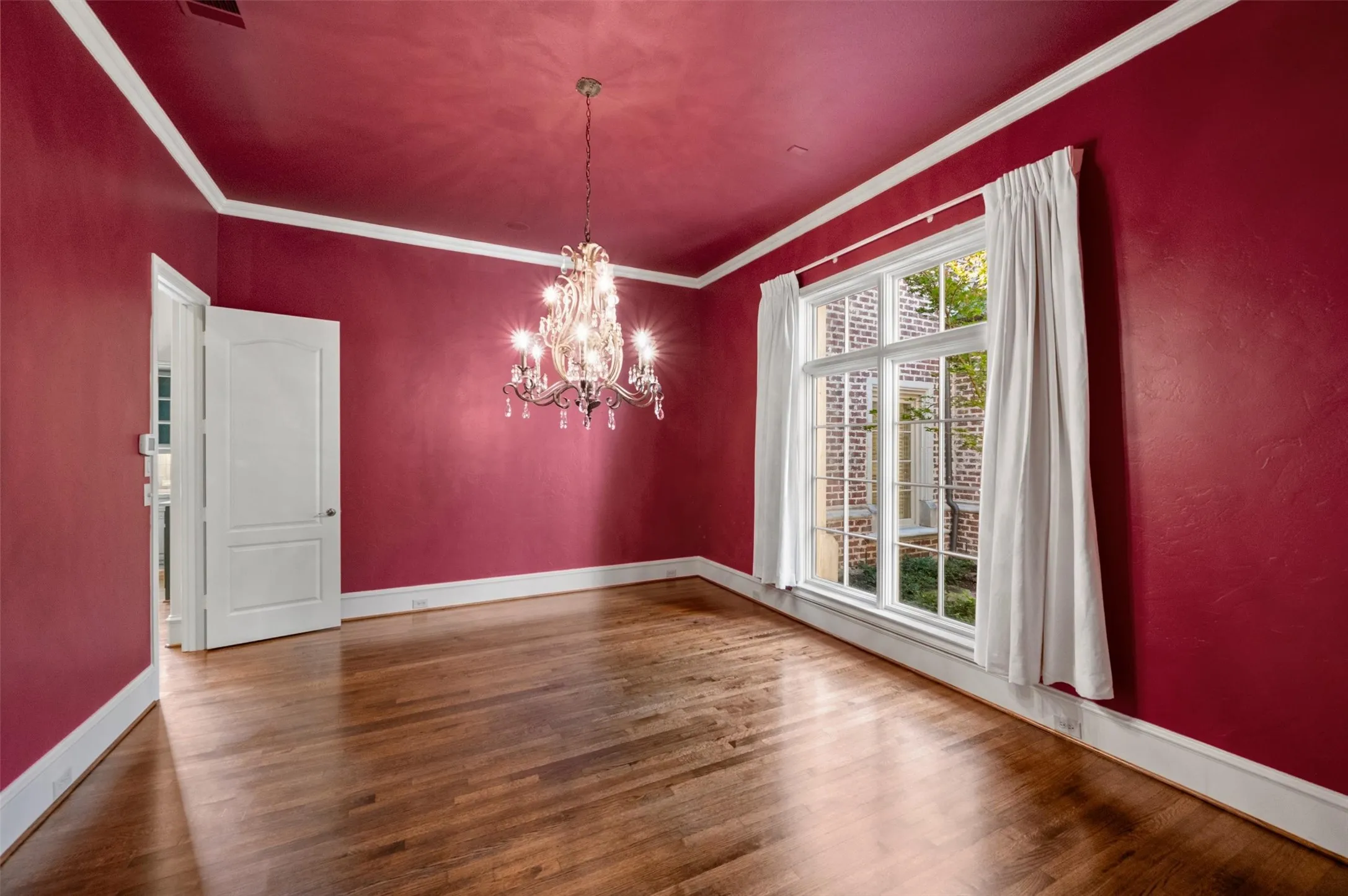 Stately chandelier and windows looking to a small courtyard out front.