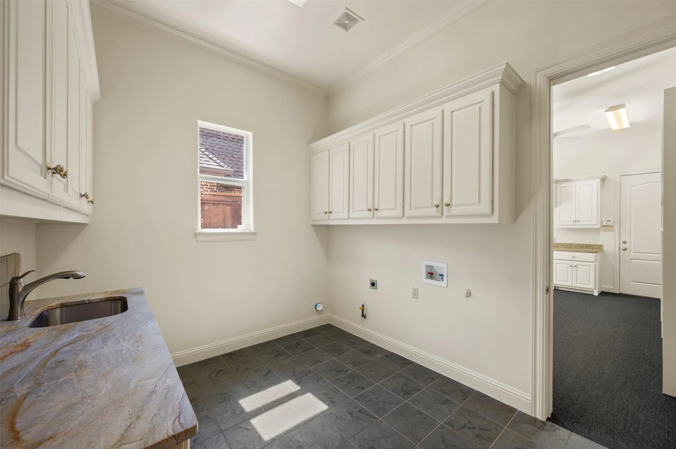 Laundry Room with matching countertops as kitchen, sink and storage.