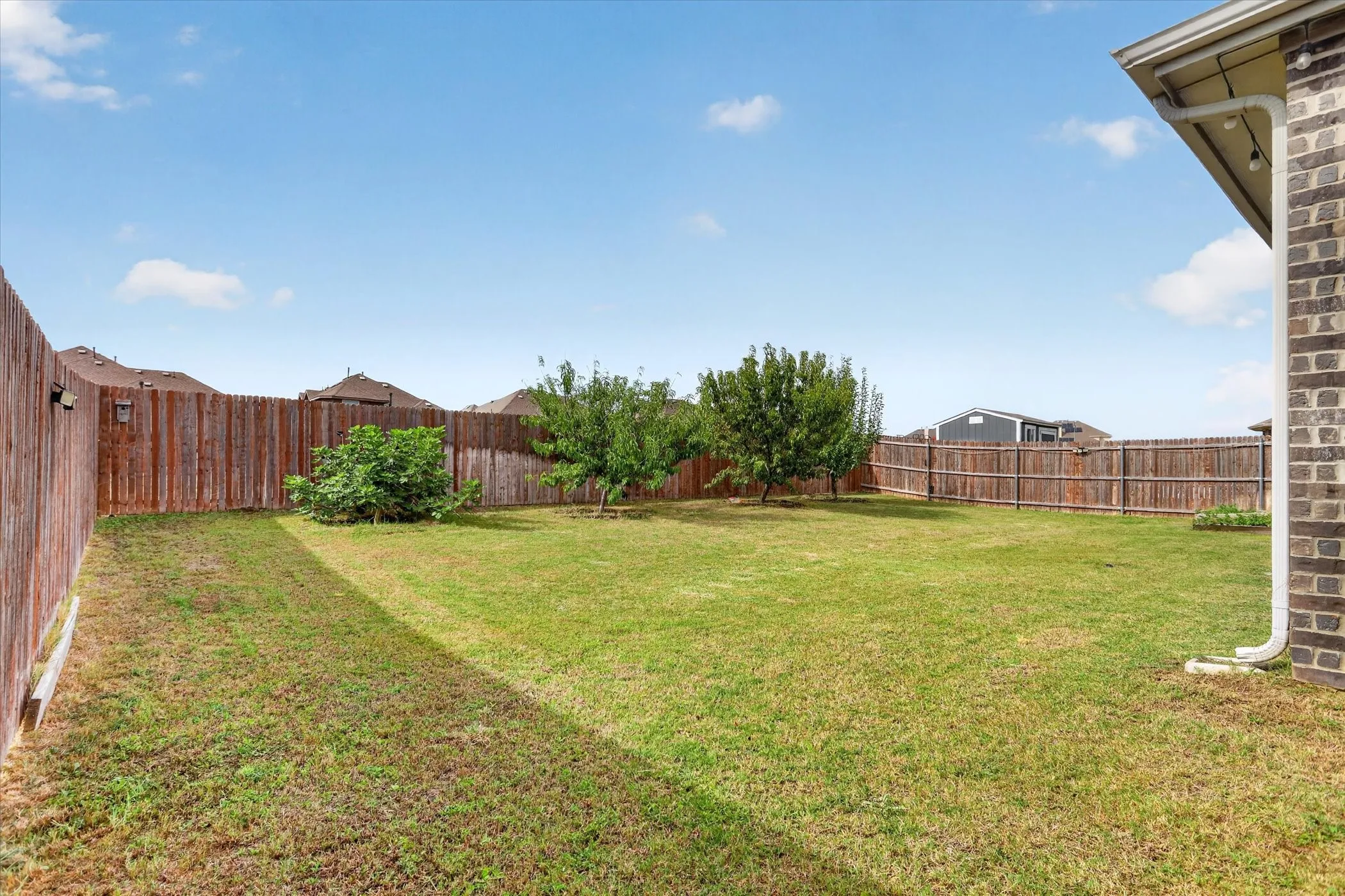 Expansive yard featuring a manicured lawn, established privacy fencing, and mature trees
