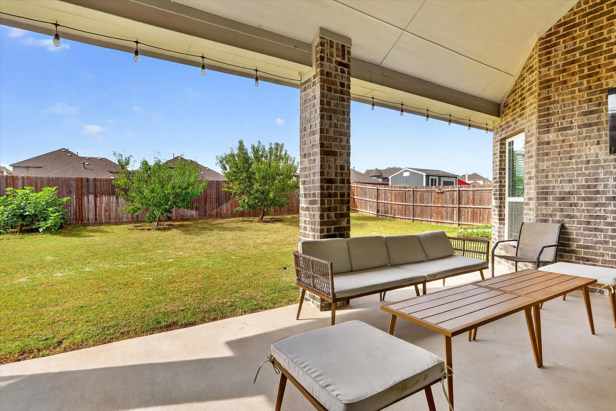Covered patio with a concrete surface, brick support column, and brick exterior wall