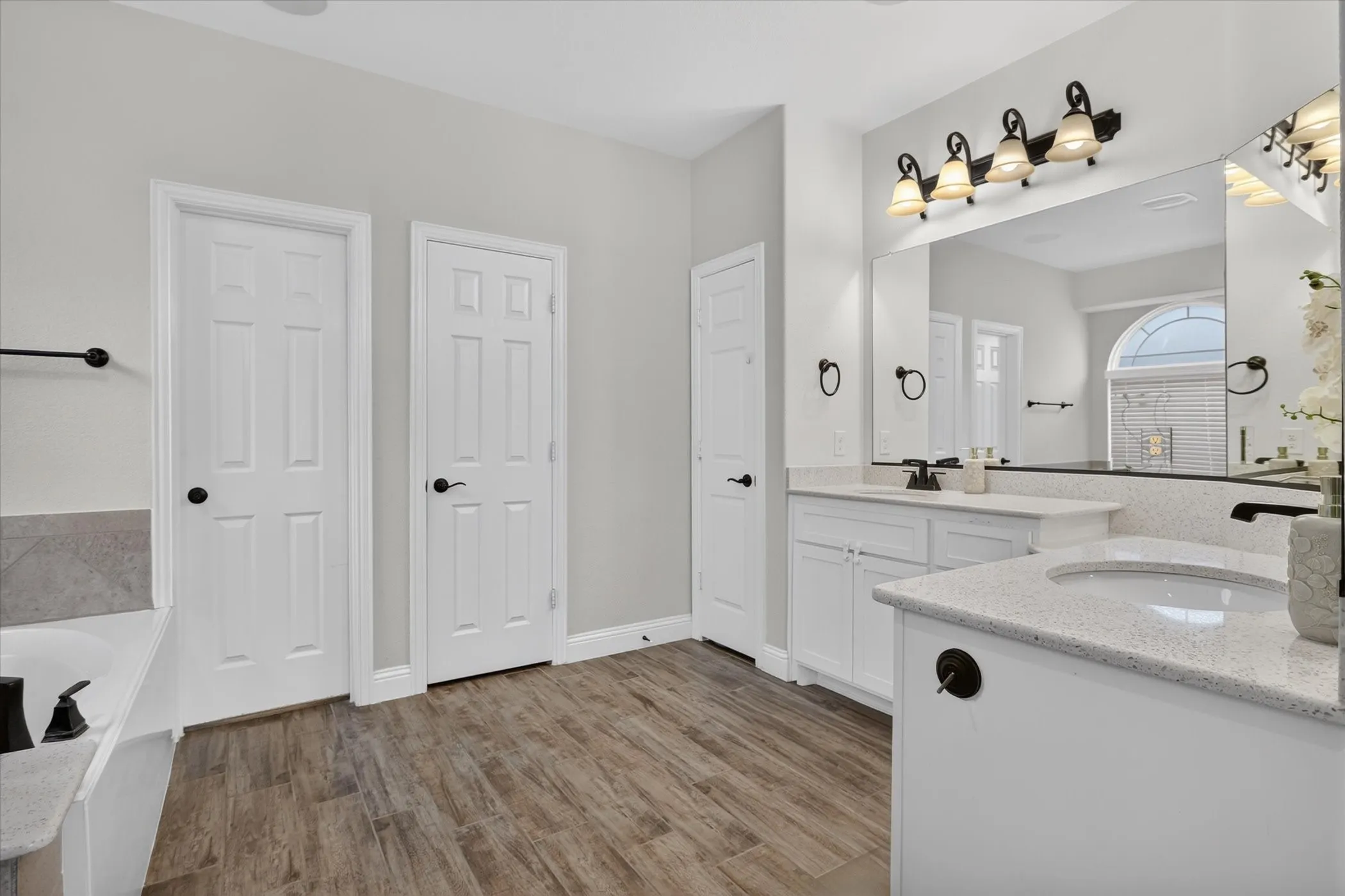 Dual vanities with integrated sinks, white cabinetry, and light-toned countertops