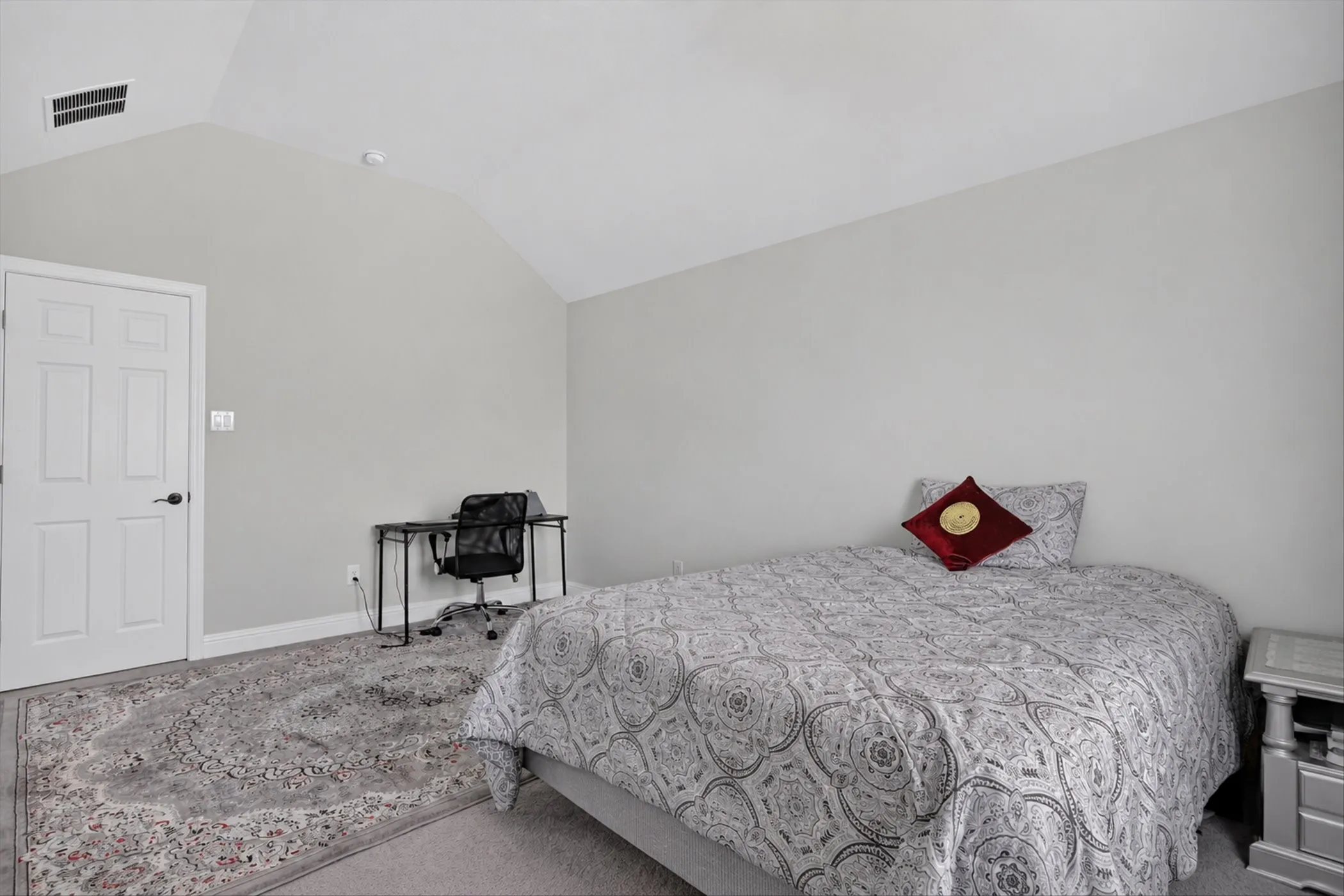 Vaulted ceiling with recessed lighting, white panel door, light gray wall paint, and gray carpeting