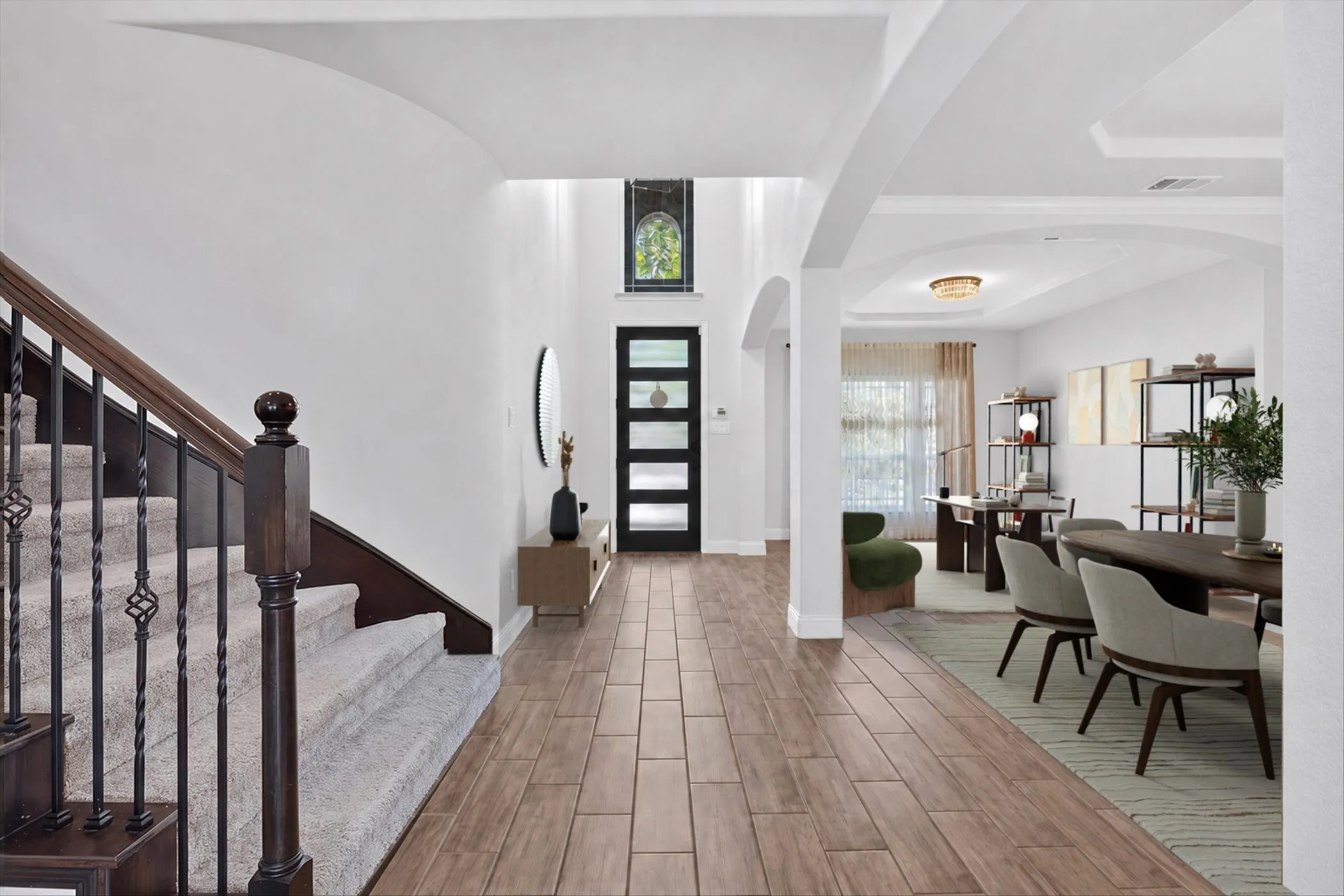 Wood-finish tile flooring throughout the entry, staircase with wood handrails and wrought iron balusters, arched hallway openings, and recessed lighting