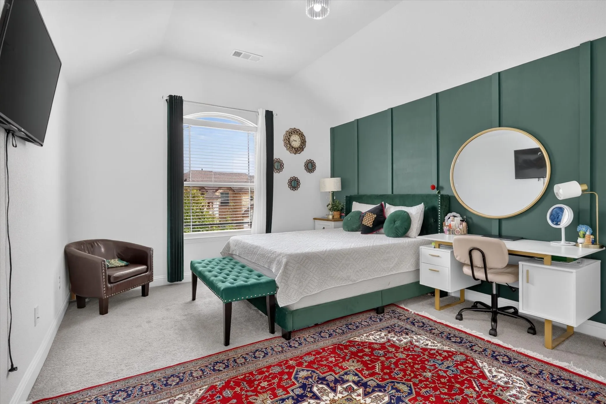 Vaulted ceiling with an arched window, featuring carpet flooring and a built-in paneled wall