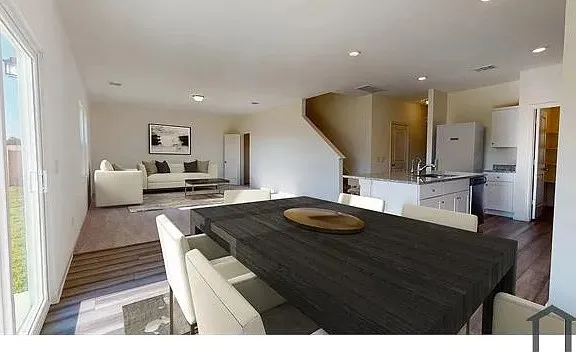 Open-concept living area with wood-finish flooring, recessed lighting, kitchen island, and sliding glass door